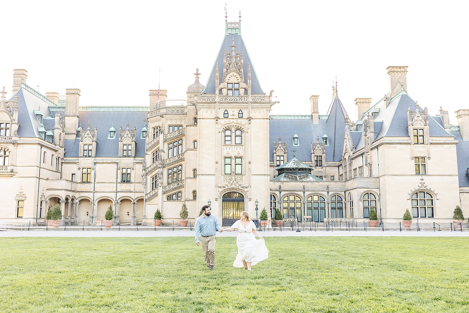 couple walking in front grand estate at Biltmore Estate in Asheville, NC