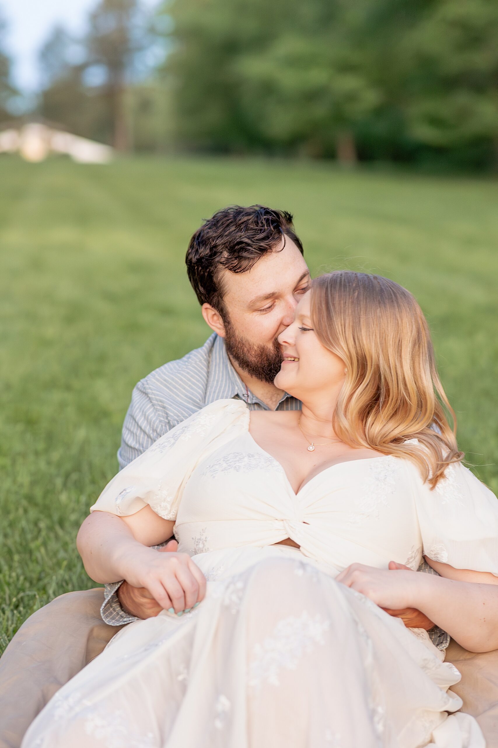 candid engagement photo of couple sitting on lawn