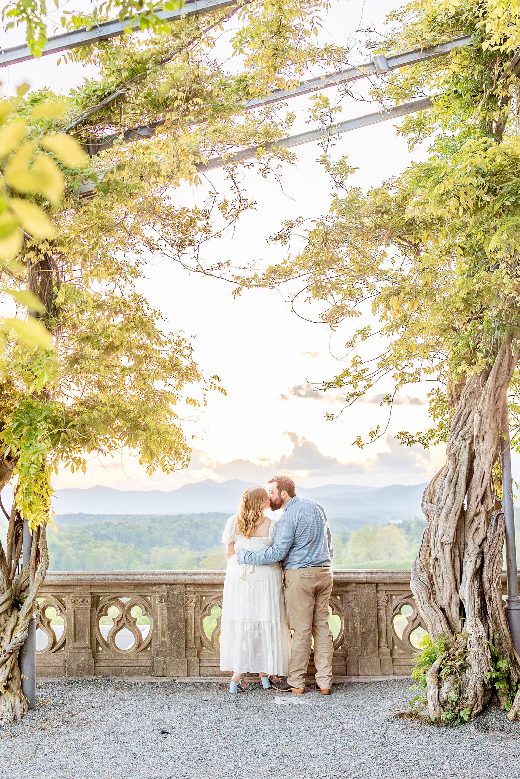 sunset engagement photo of couple kissing by balcony