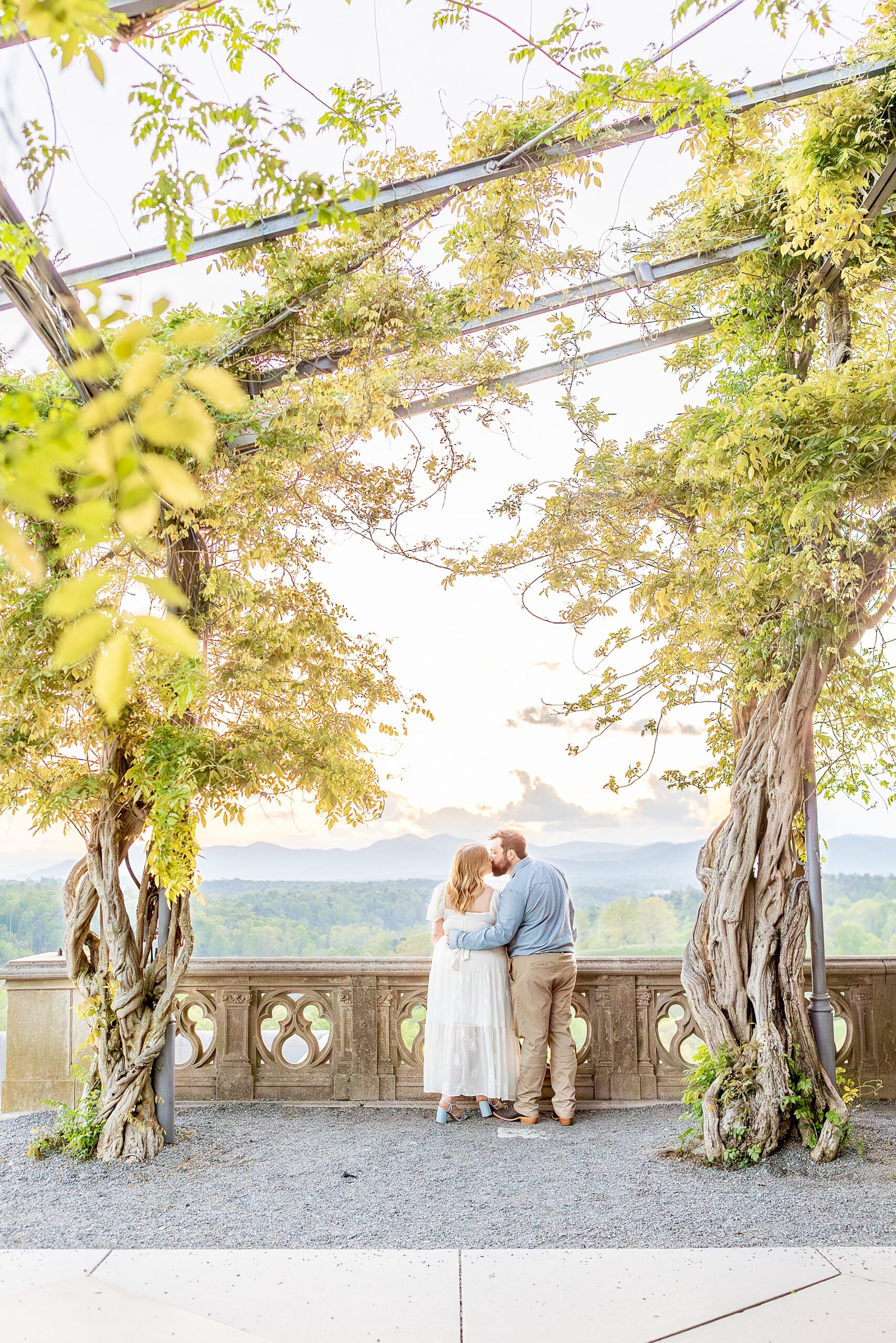 couple kiss on balcony overlooking landscape below