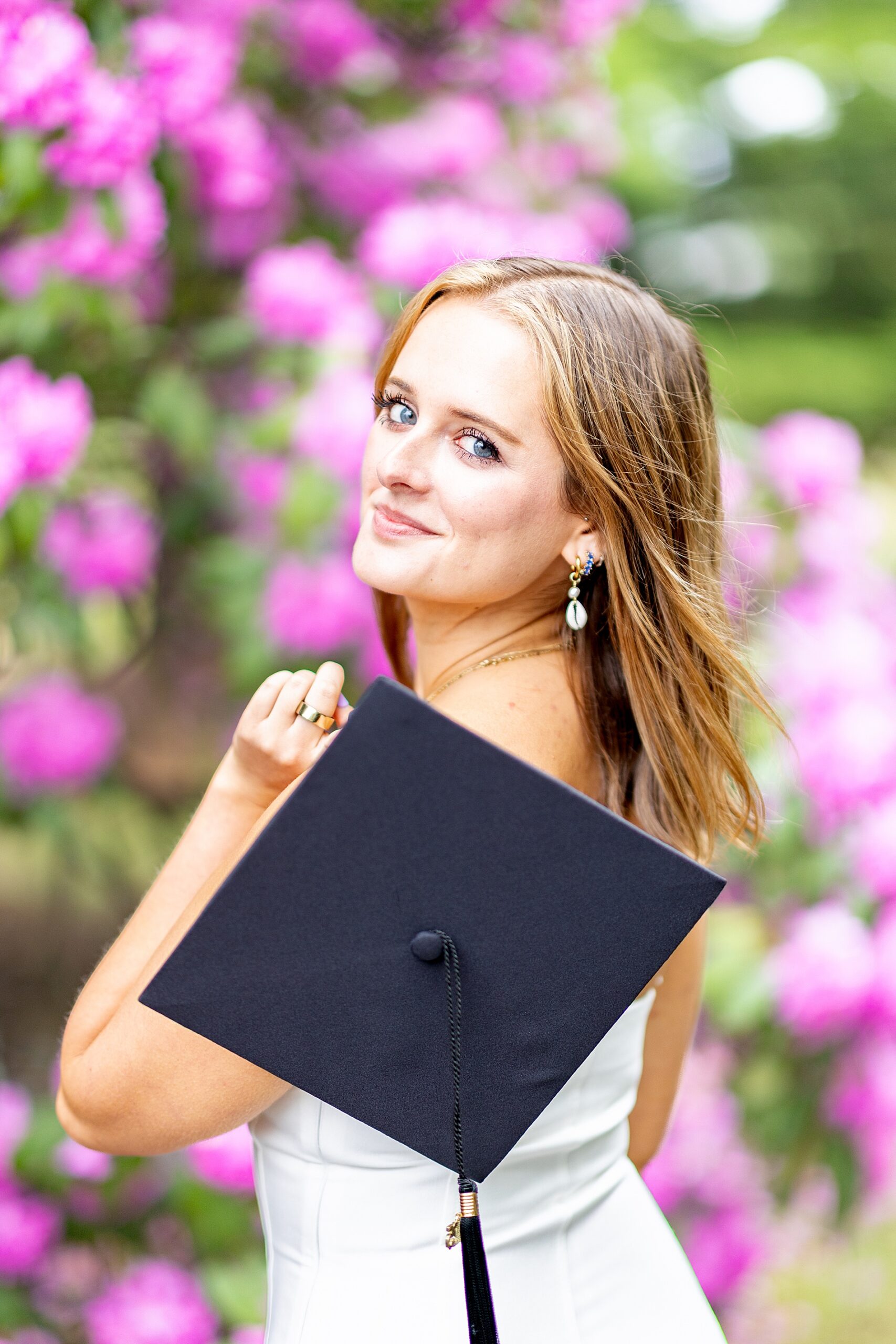 college graduate holds cap in hand over shoulder