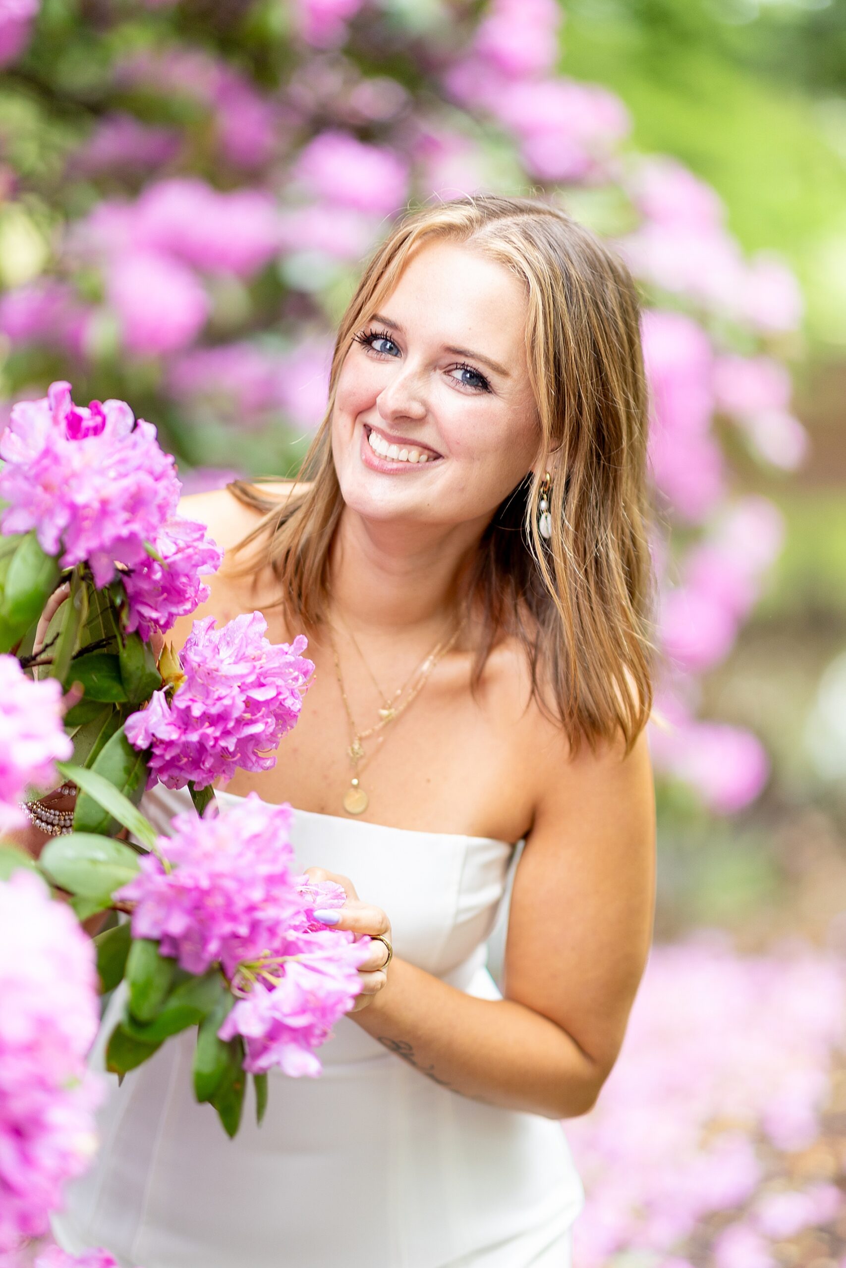woman stands by blooming pink flowers during spring session