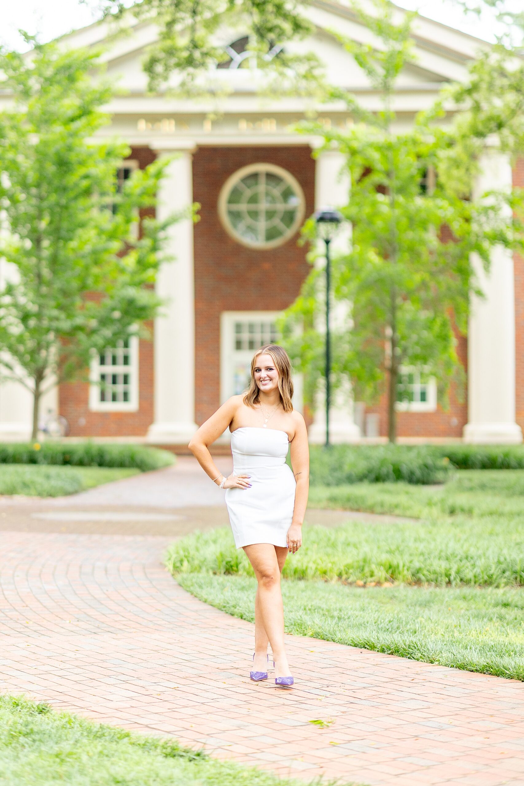 woman in white dress stands in front of Furman University building