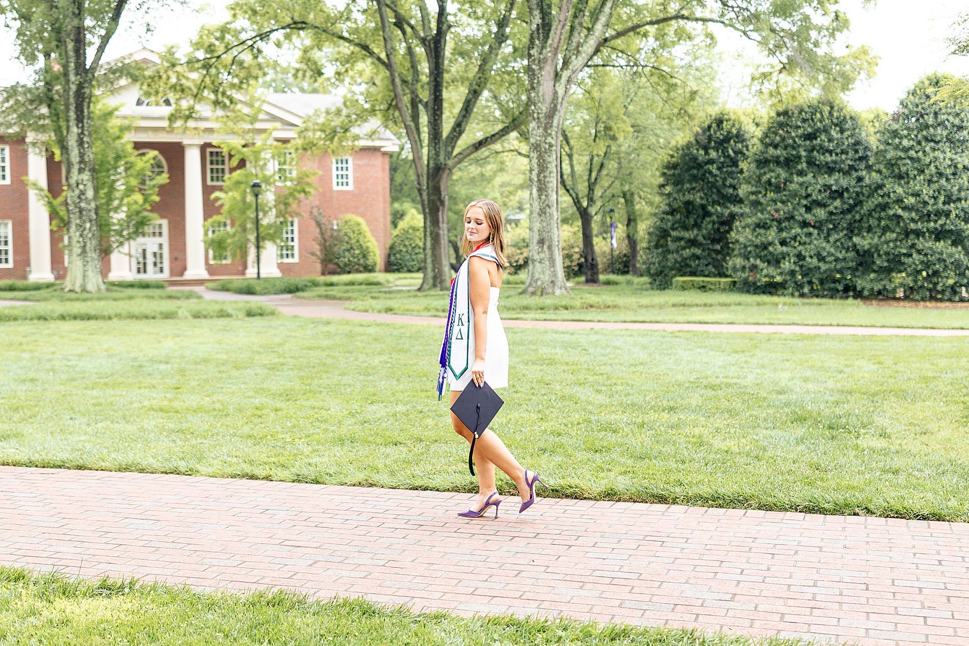 senior walk along brick sidewalk on university campus