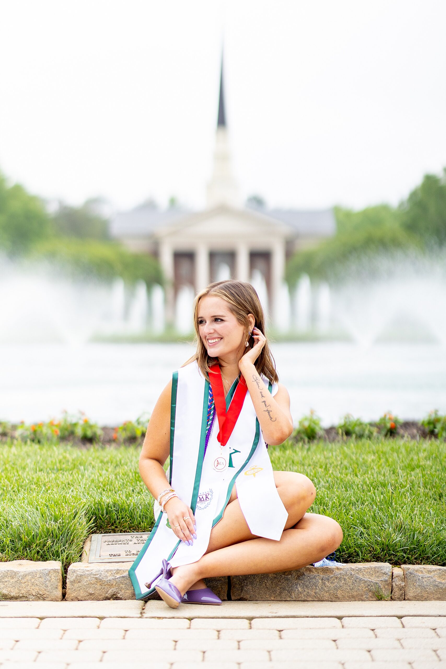 woman sits in front of fountain at Furman University during Grad Session