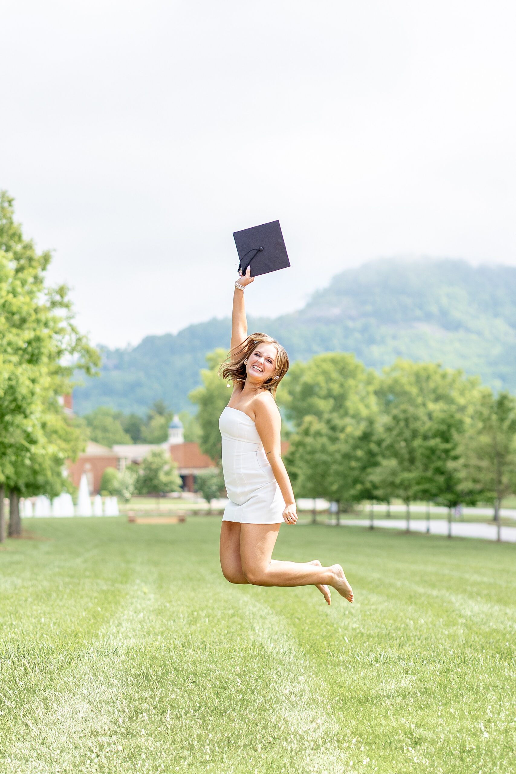 college graduate jumps in the air holding graduation cap