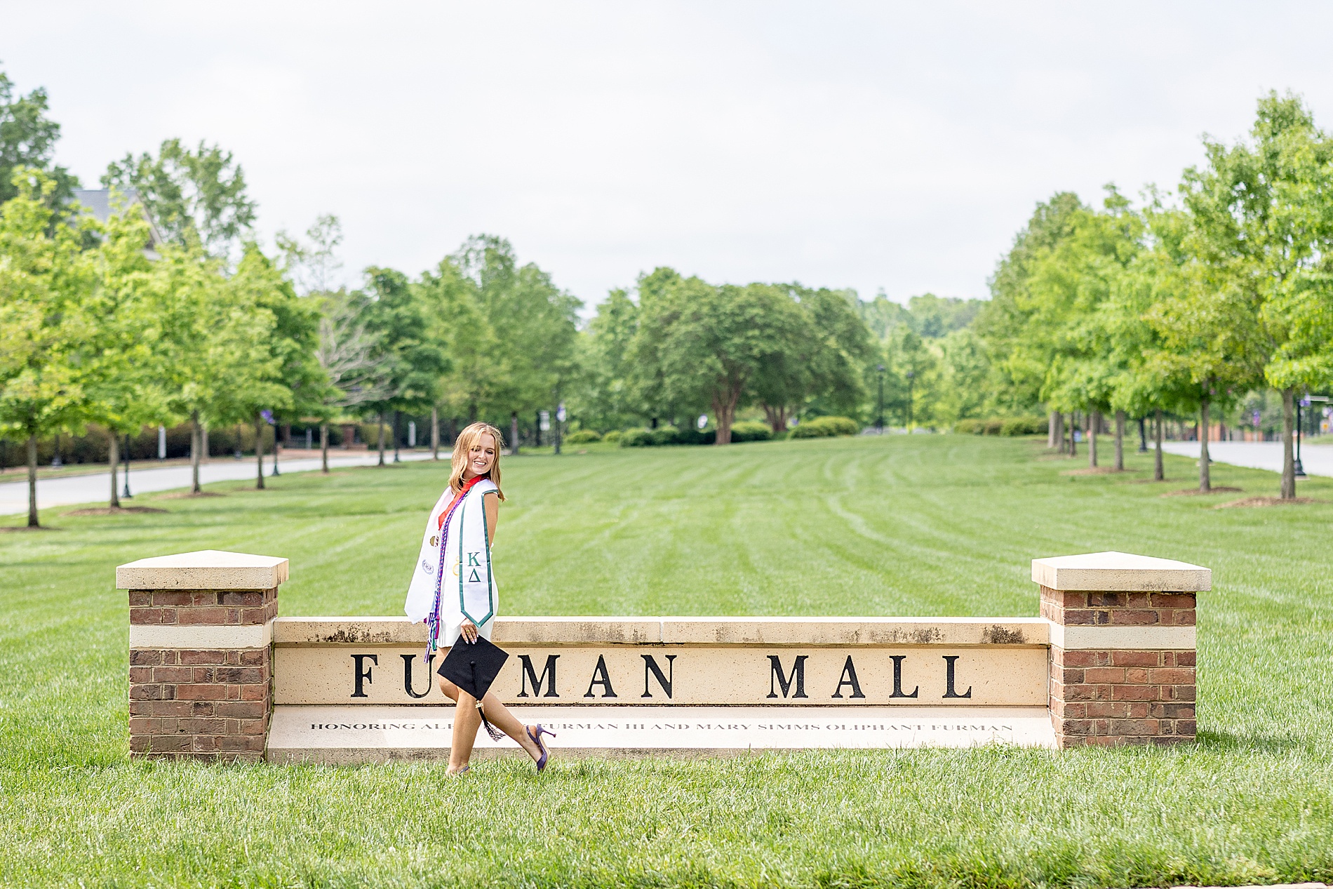 woman walks in front of Furman University sign during Grad Session