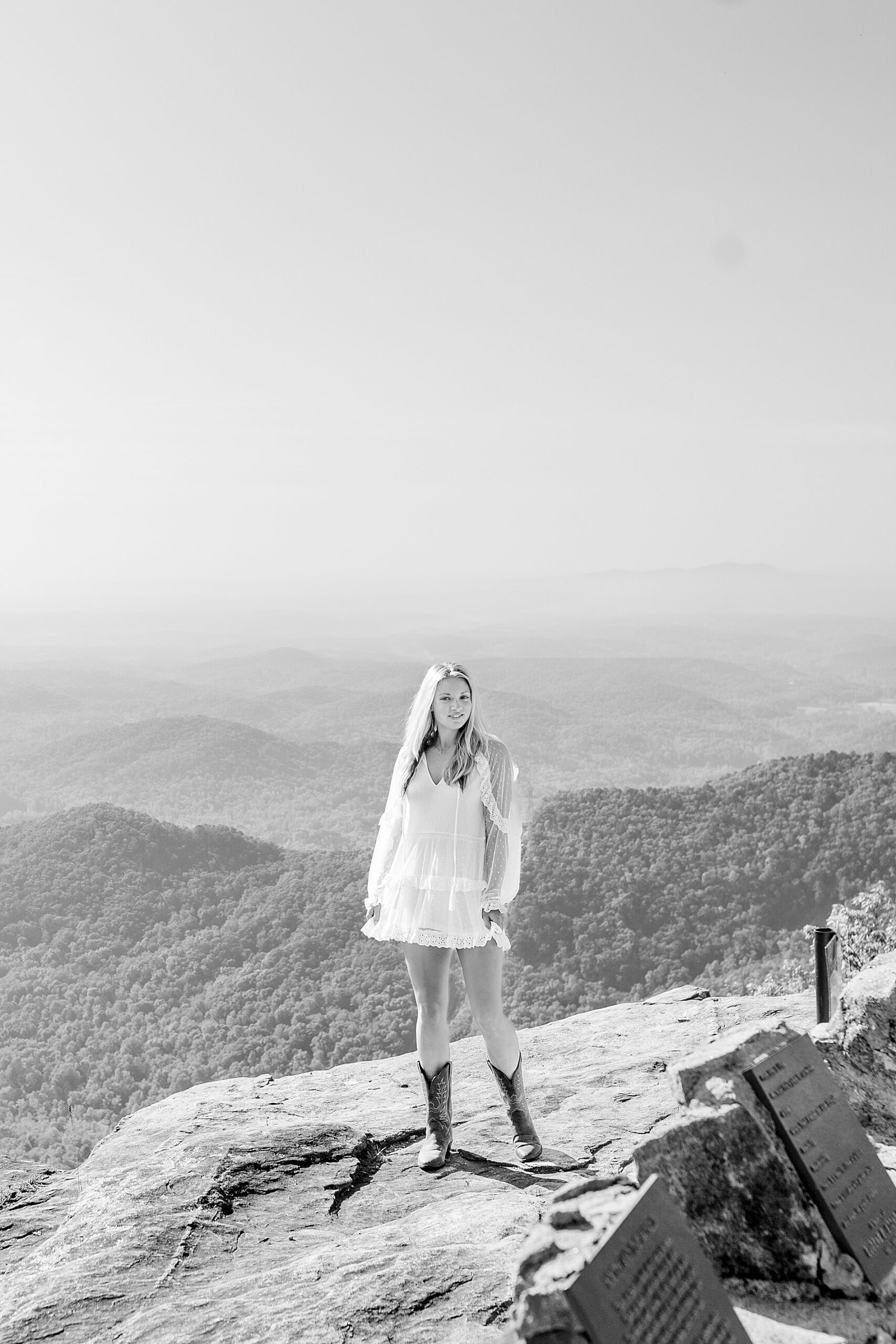 girl standing on rocky ledge overlooking mountains