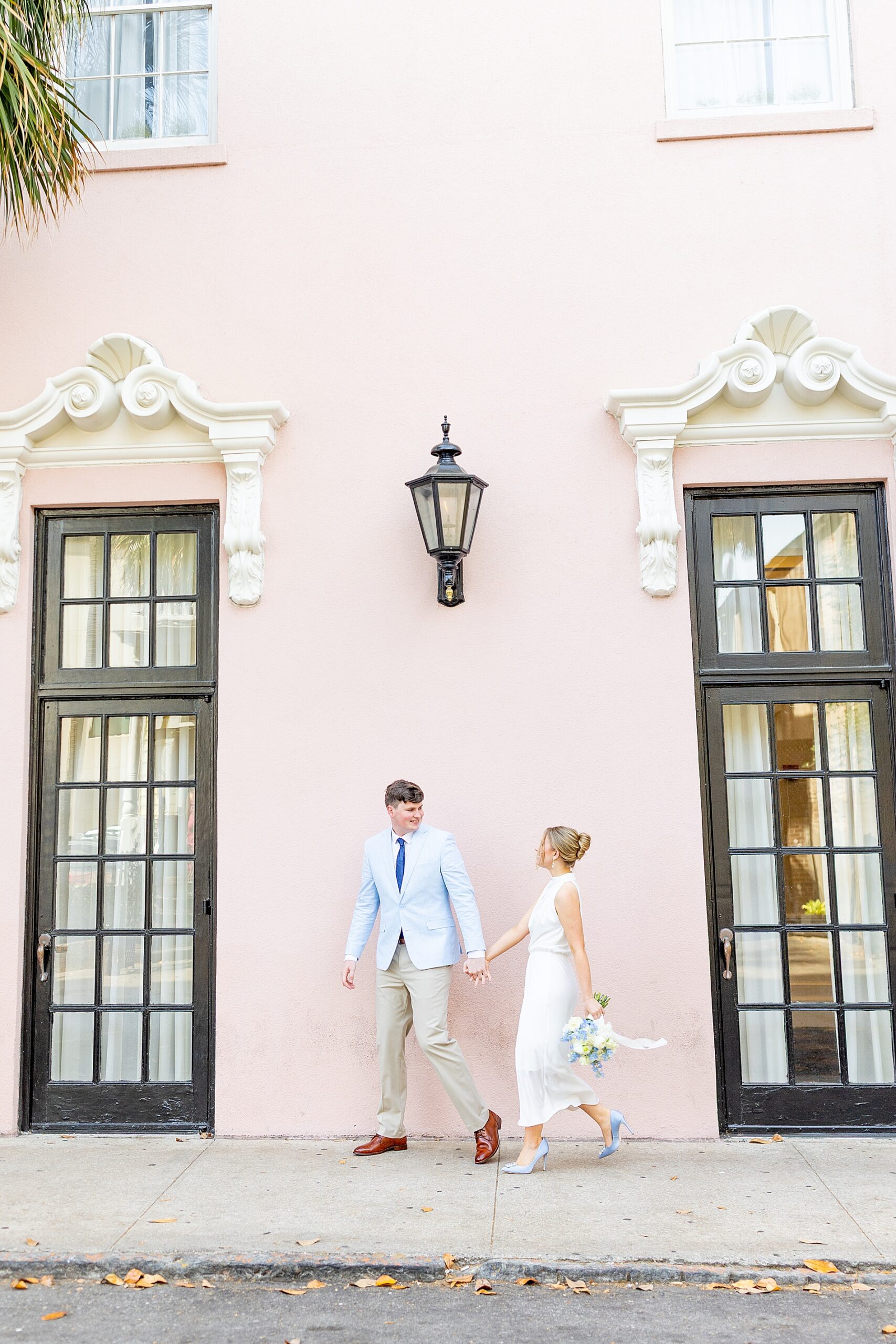 romantic engagement photos in Charleston in front of pastel pink building
