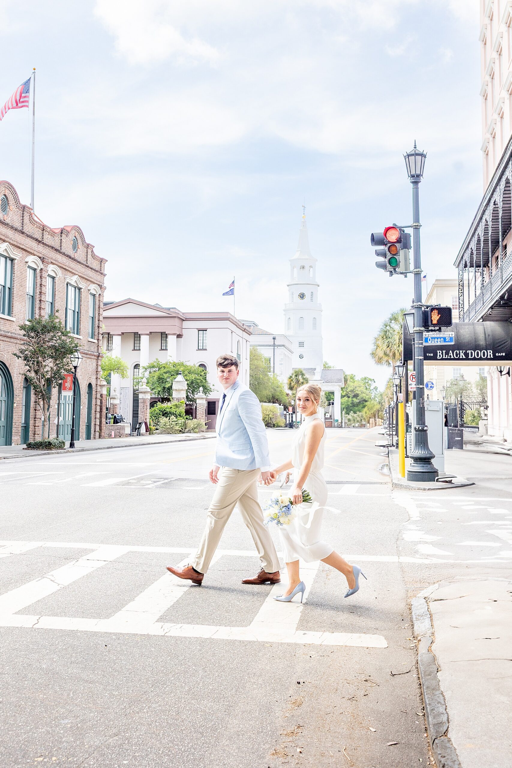 engaged couple cross the street holding hands in Charleston, SC