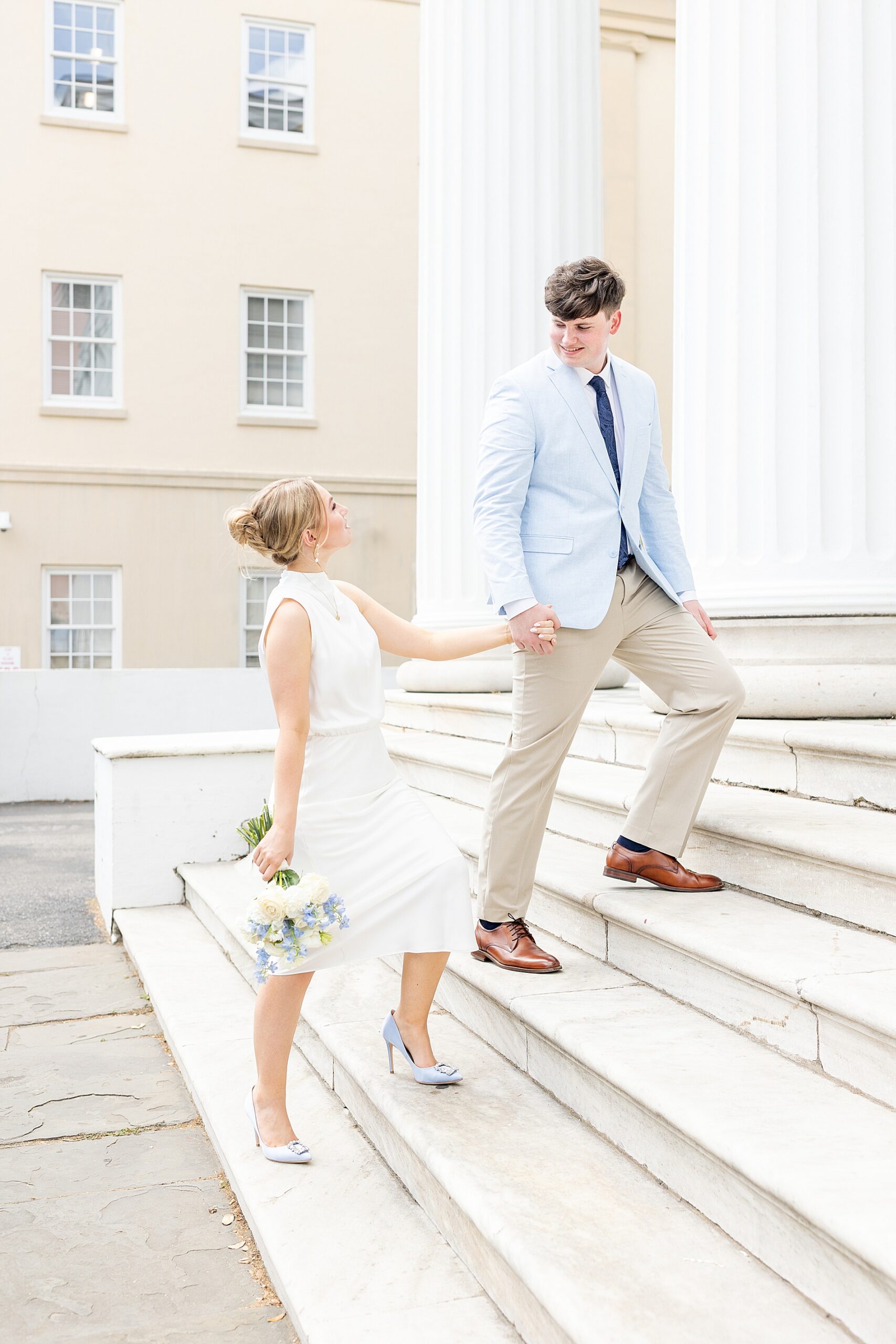 guy leads fiancé up the stairs of building