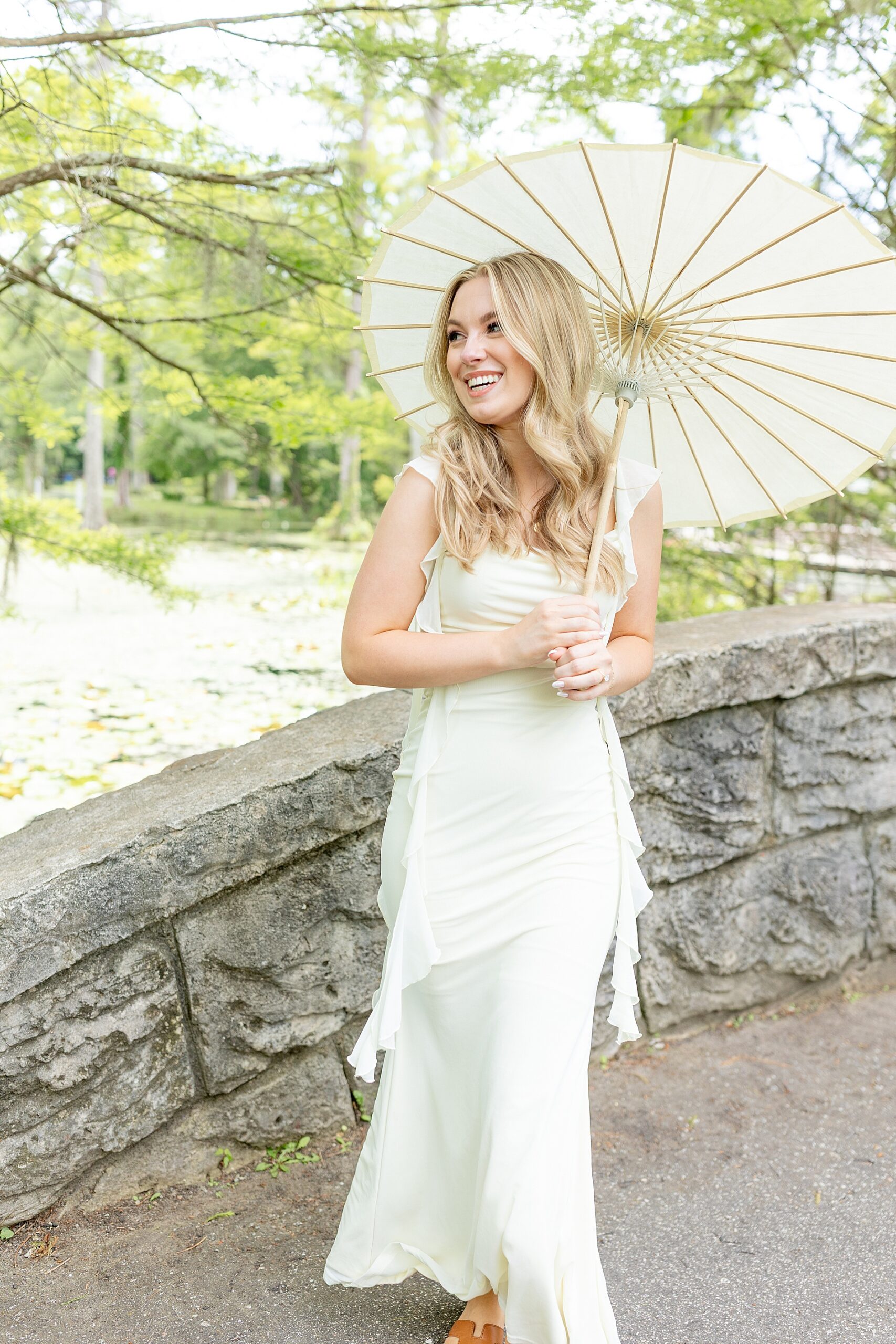 woman in white dress holds stylish umbrella during engagement session