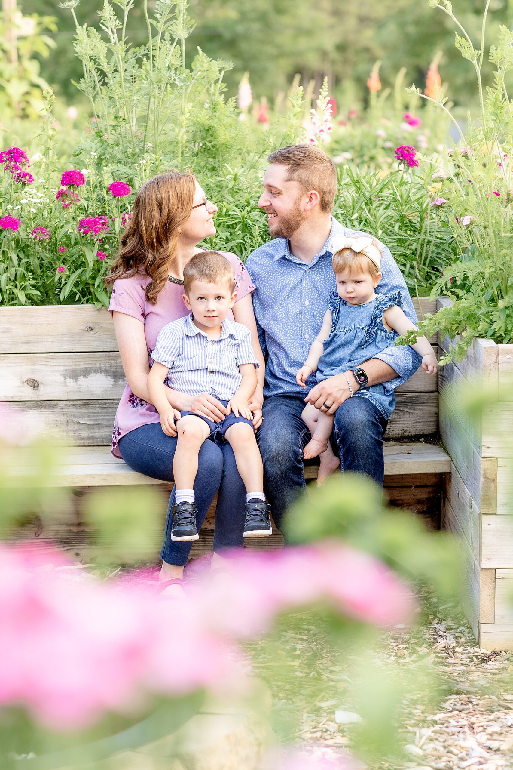 parents sit on bench holding their two kids