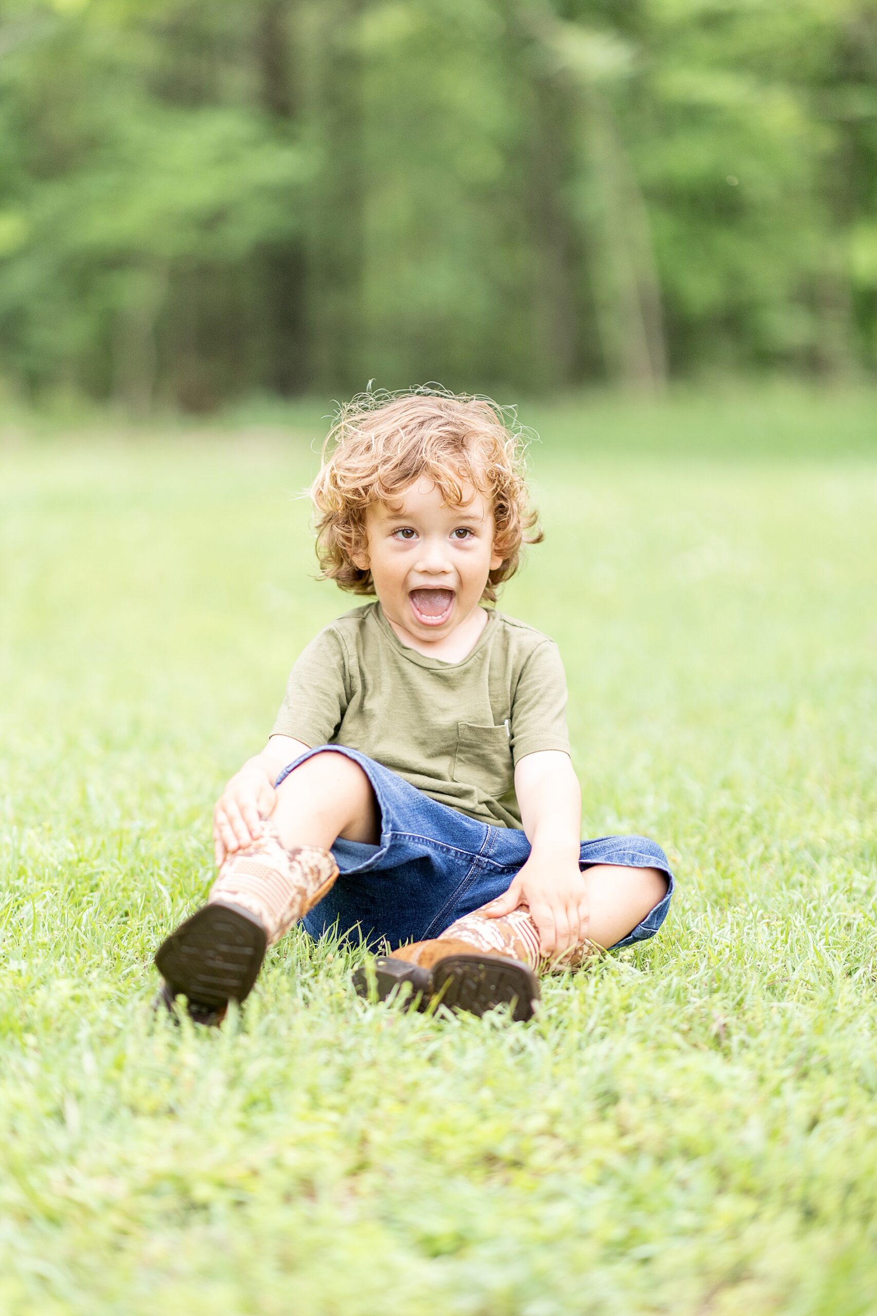 adorable little boy sits in grass