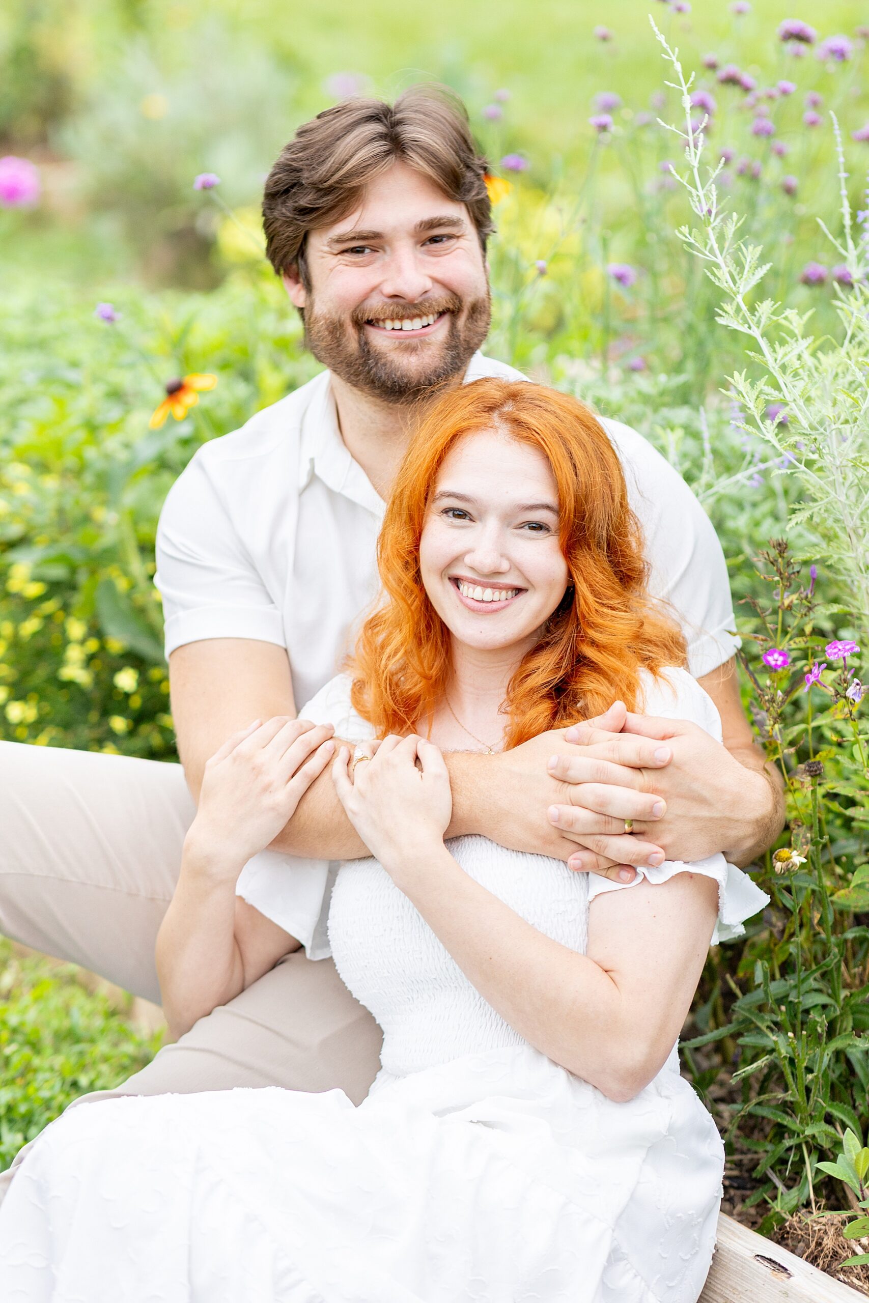 couple sit together in field of flowers