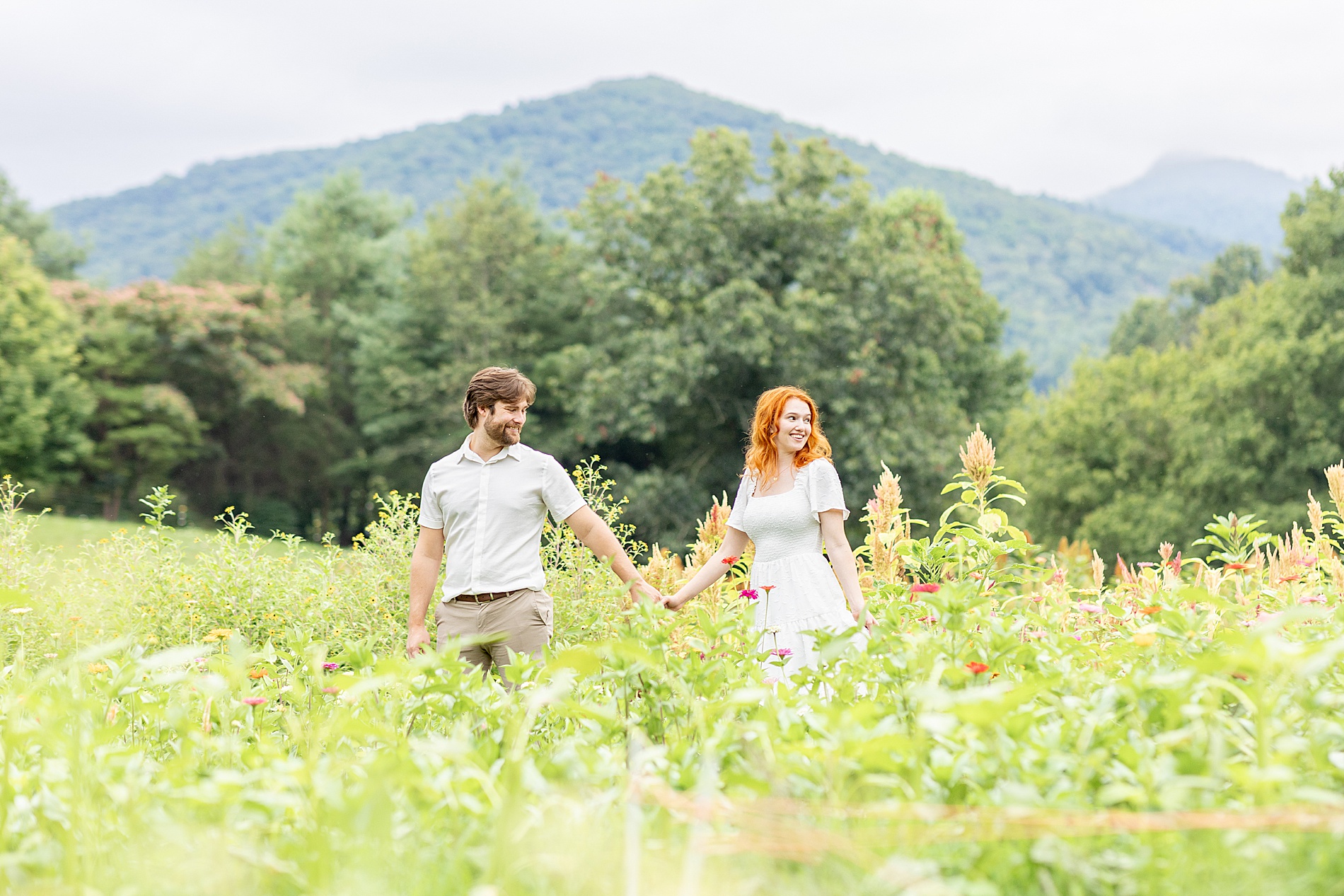 husband and wife holding hands through flower field 