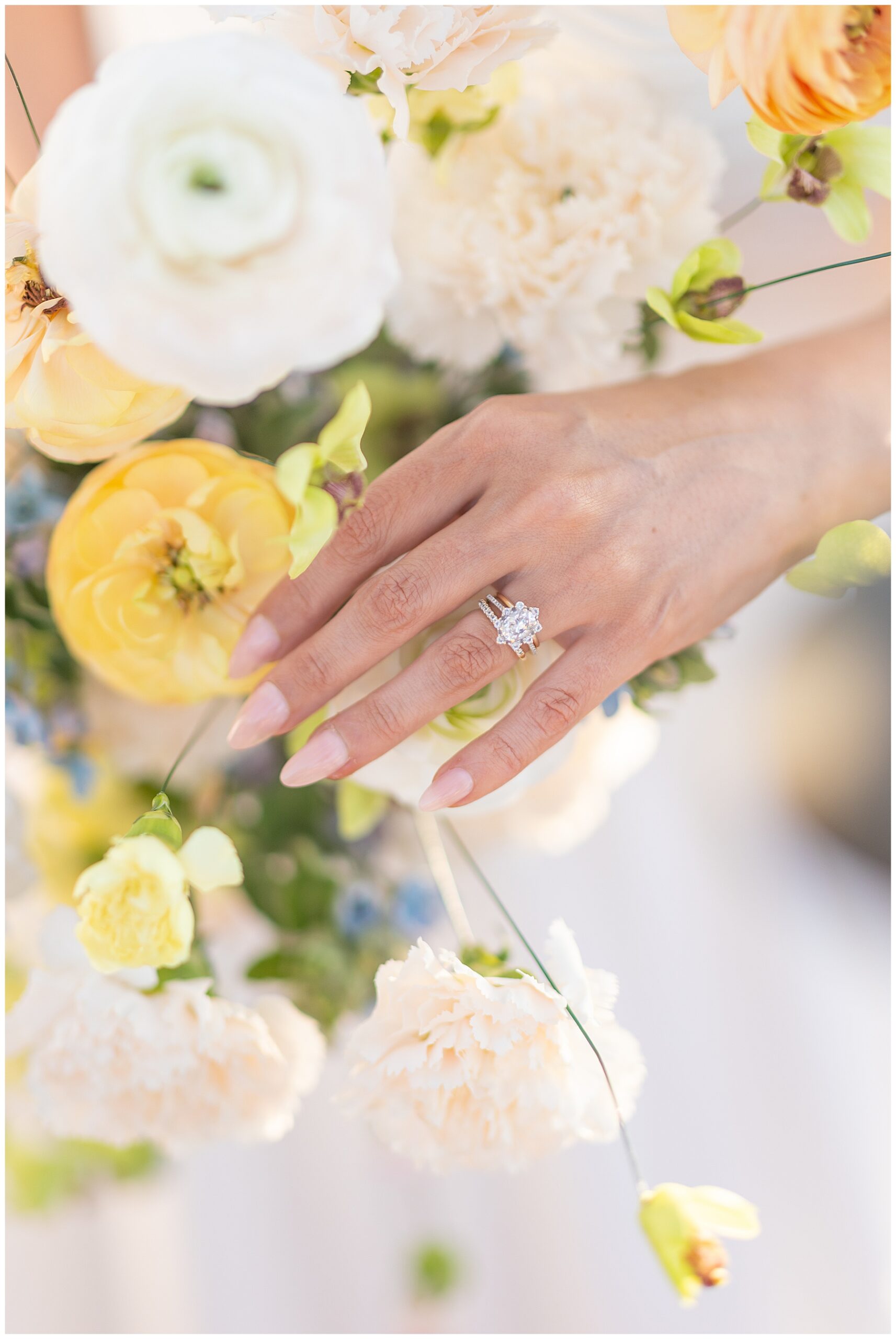 bride wearing wedding ring holding yellow and white bridal bouquet 