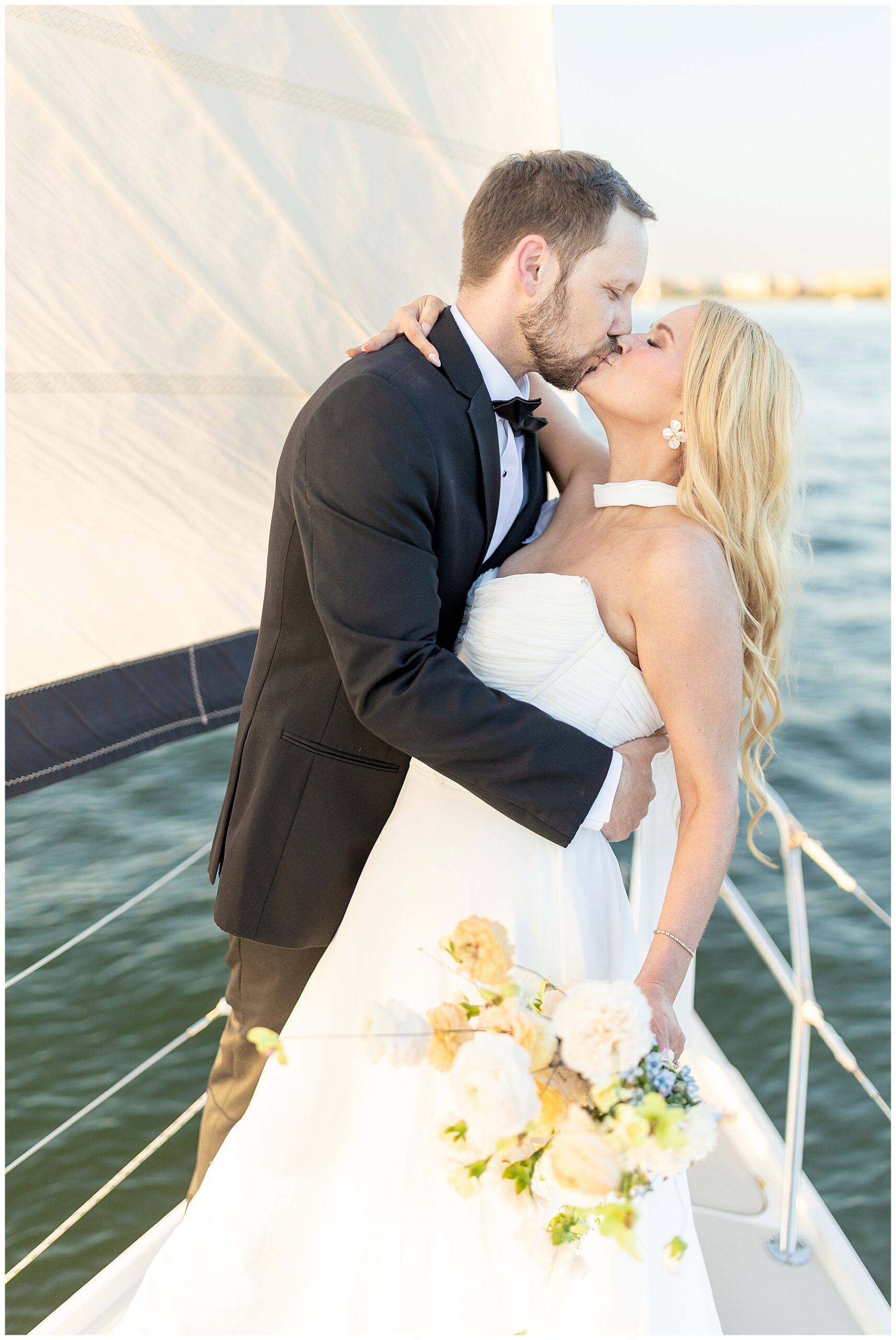 Romantic wedding portraits of newlyweds kissing on sailboat in the Charleston Harbor 