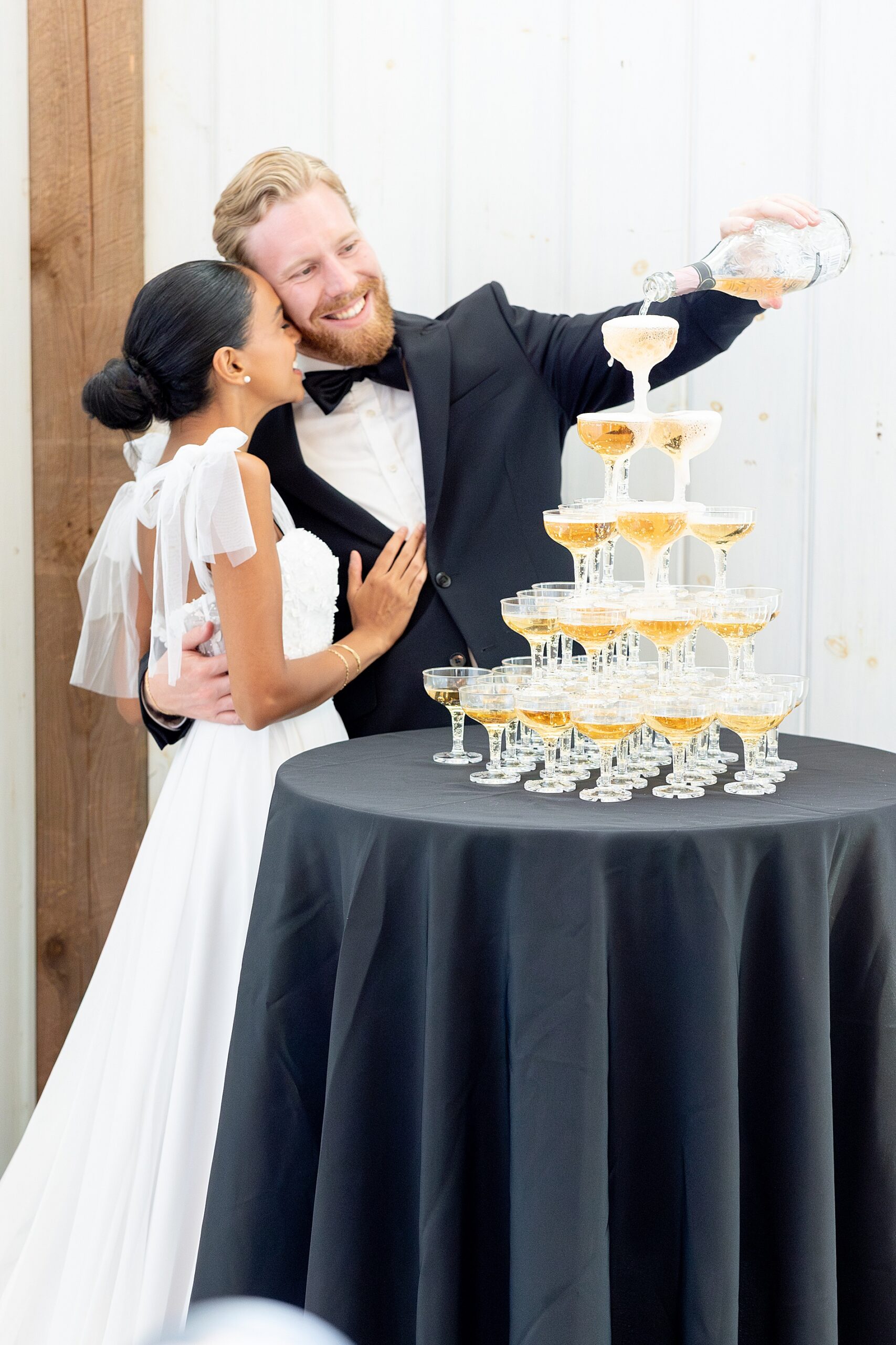 groom pours champagne over tower of glasses