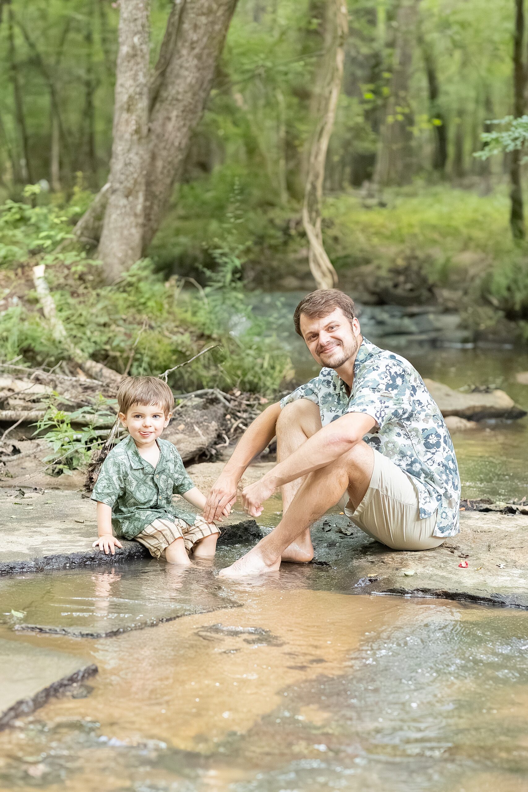 father and son sit in the creek
