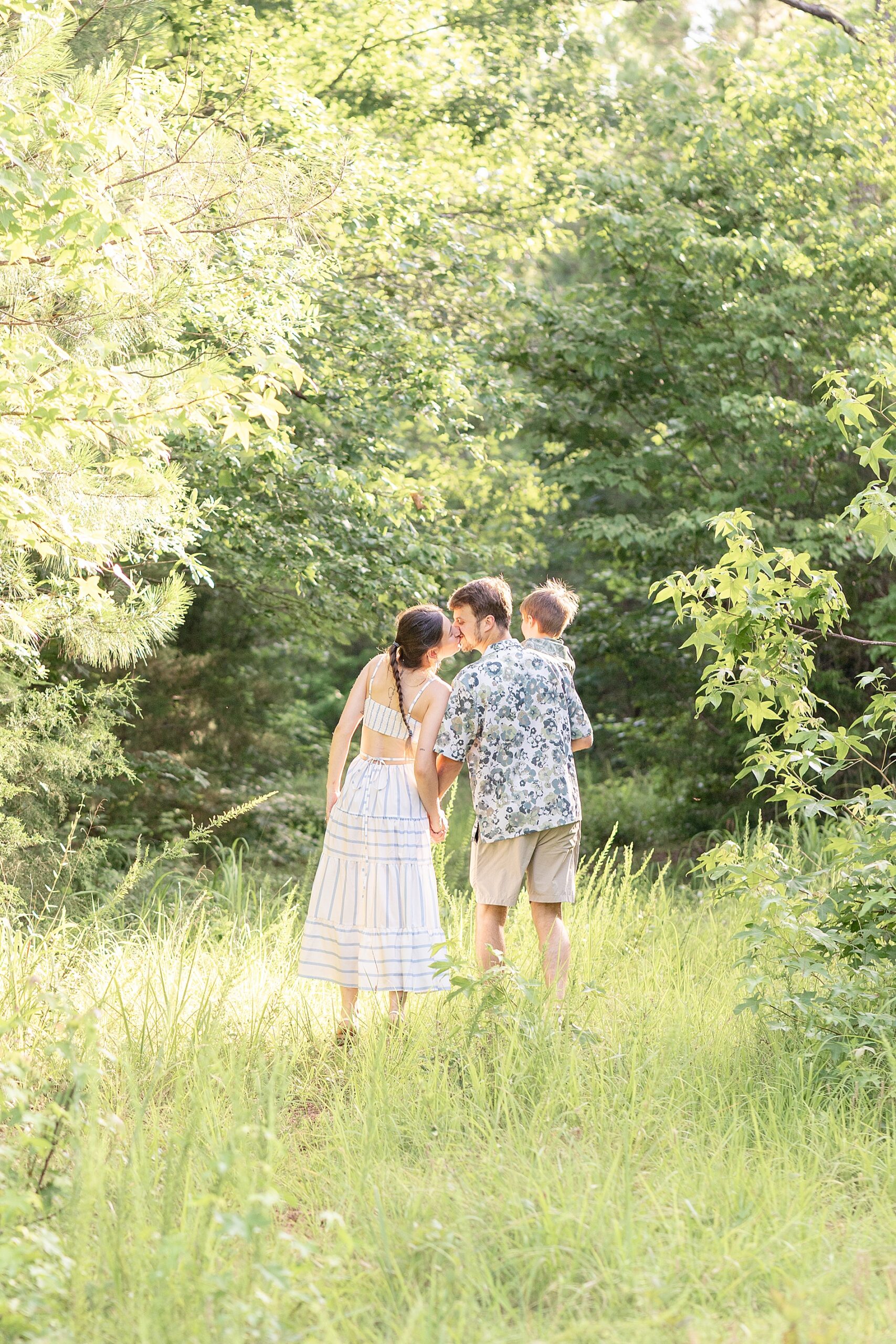 parents kiss while holding their son