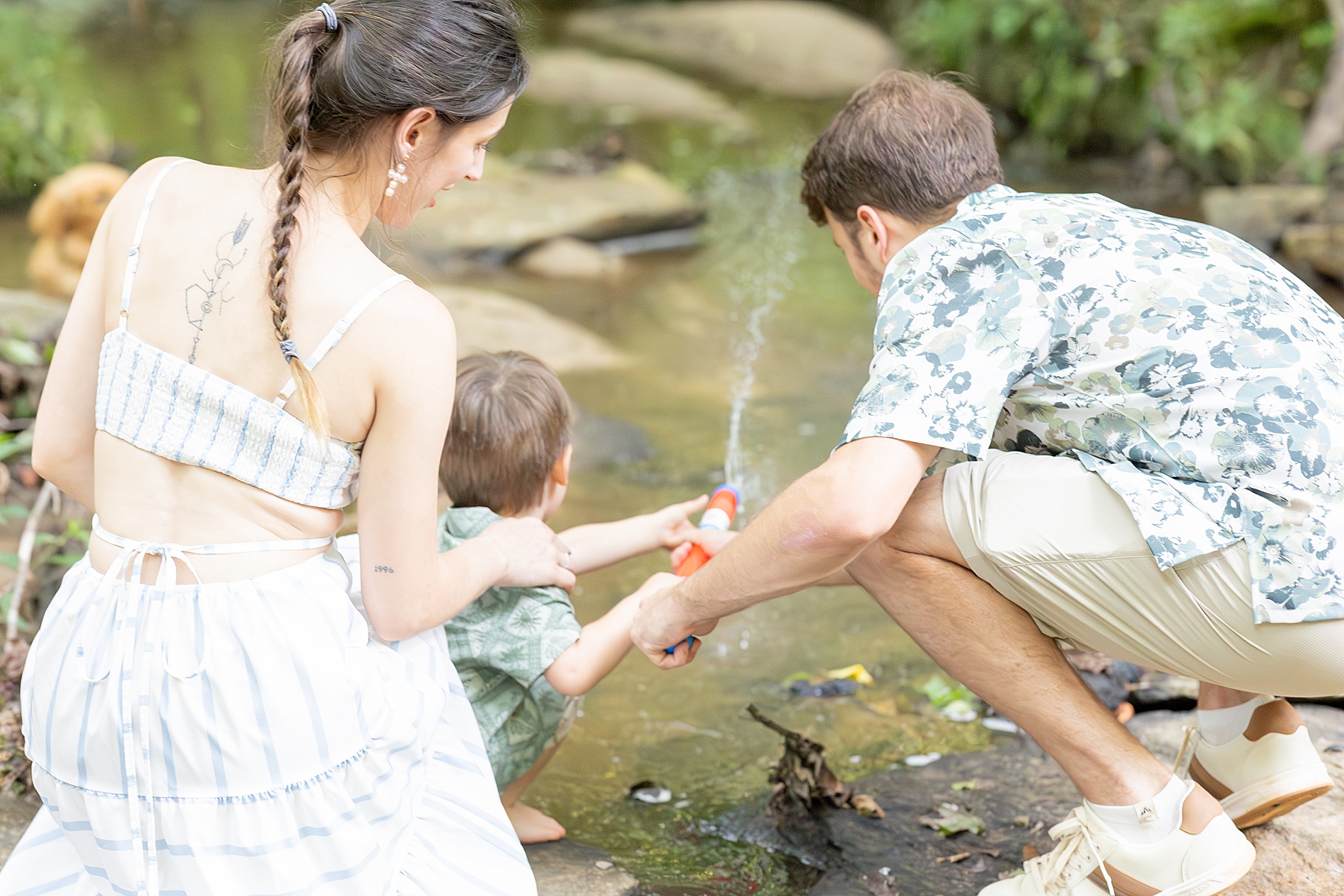 little boy playing in creek with parents