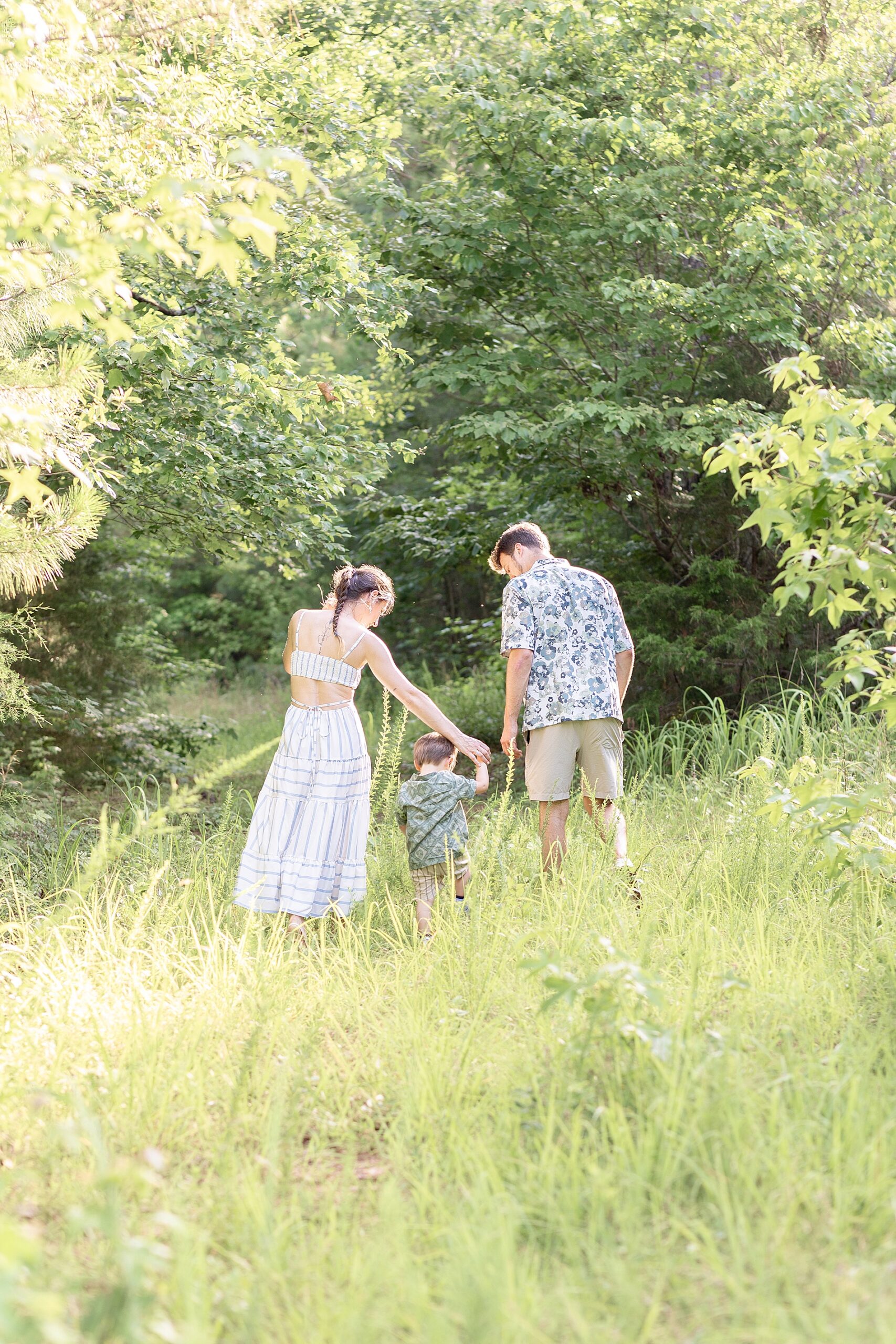 parents walk with son in tall grass