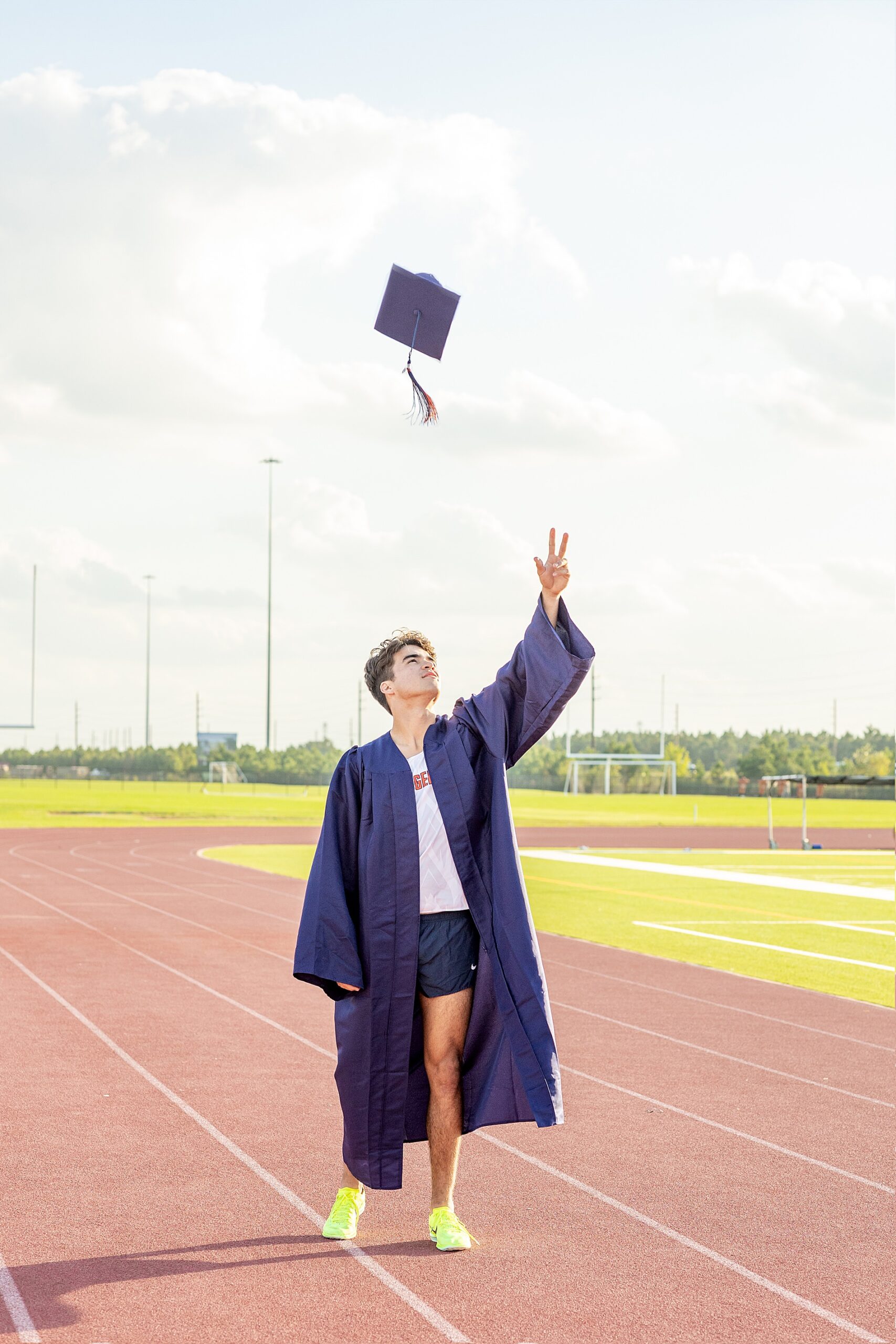 senior wearing graduation gown throws cap in the air 