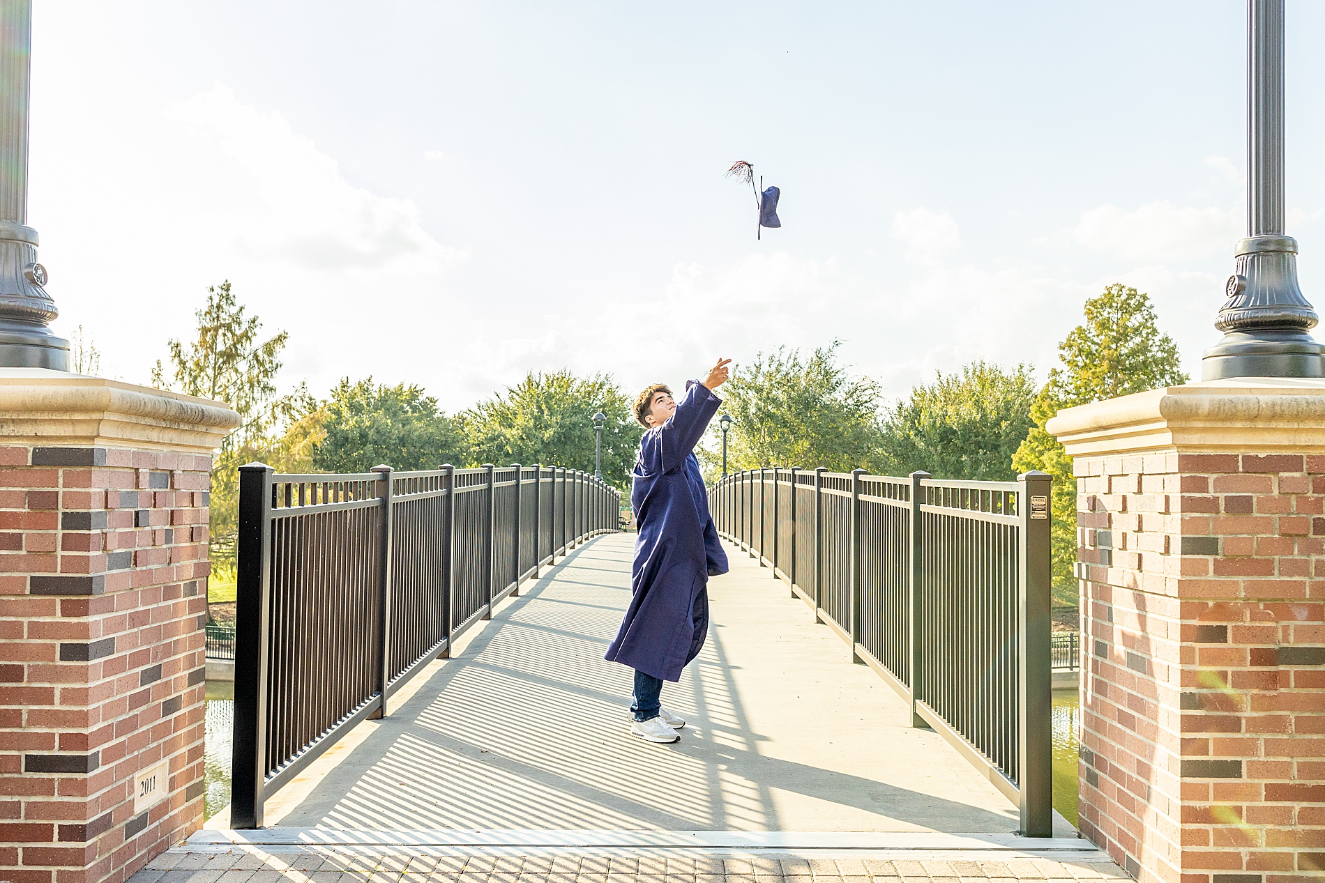 senior boy in cap and gown through cap in the air