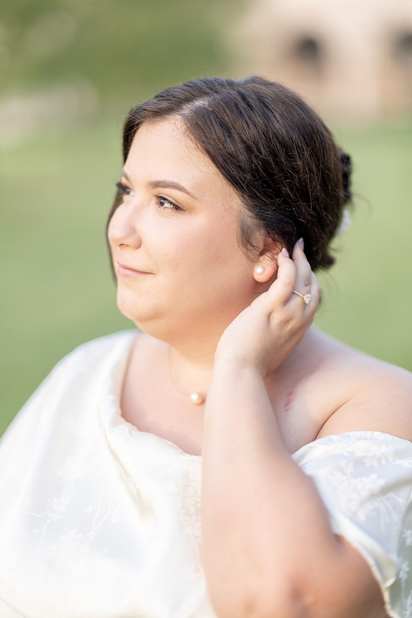 woman puts hair behind her ear showing off engagement ring