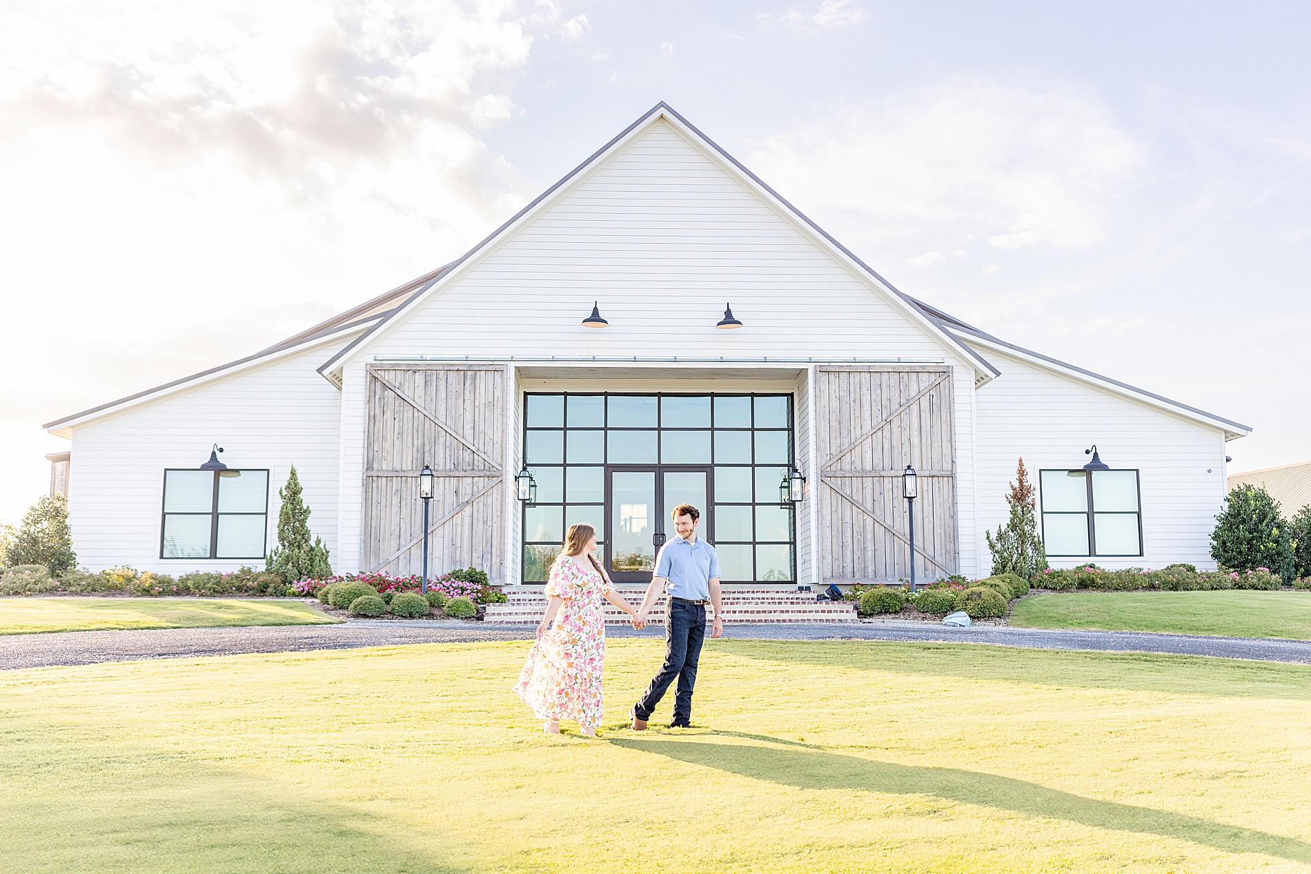 Romantic engagement photos of couple holding hands as they walk across lawn together
