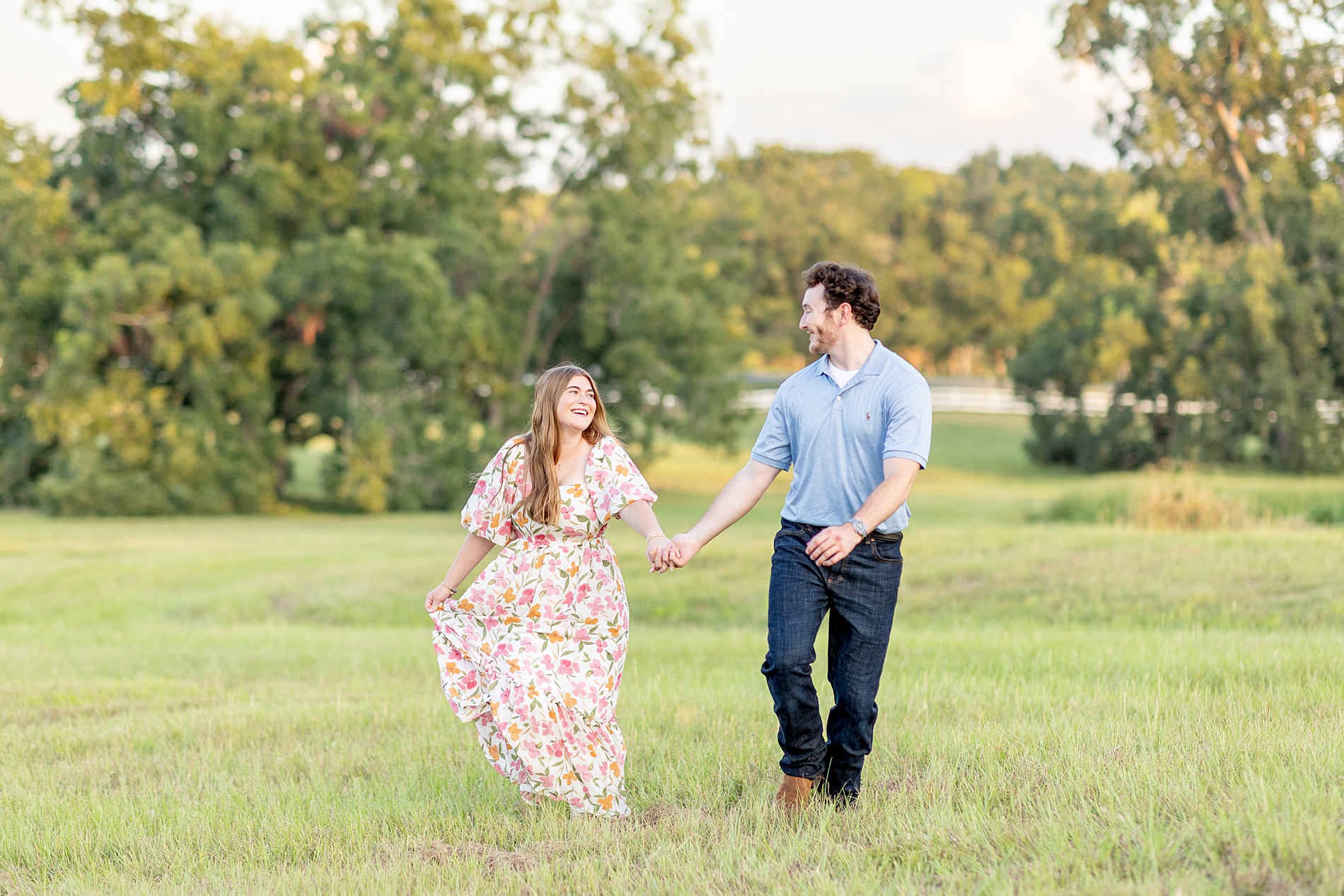 couple hold hands as they walk across field 