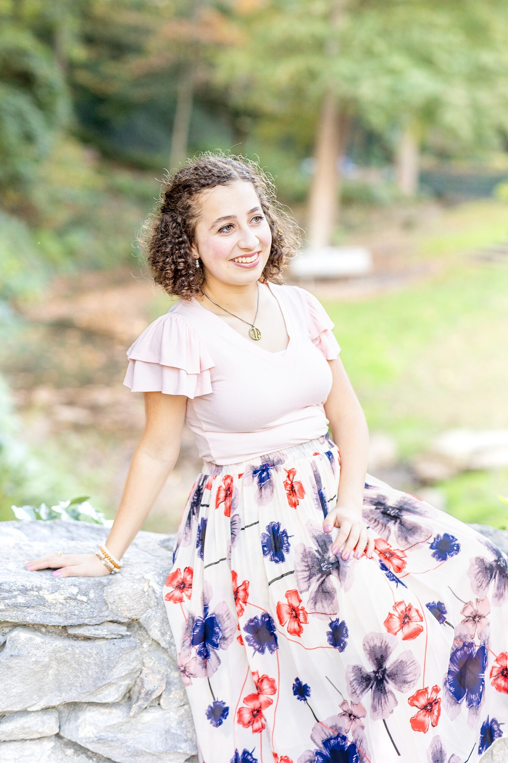 senior girl sits on rock at Falls Park