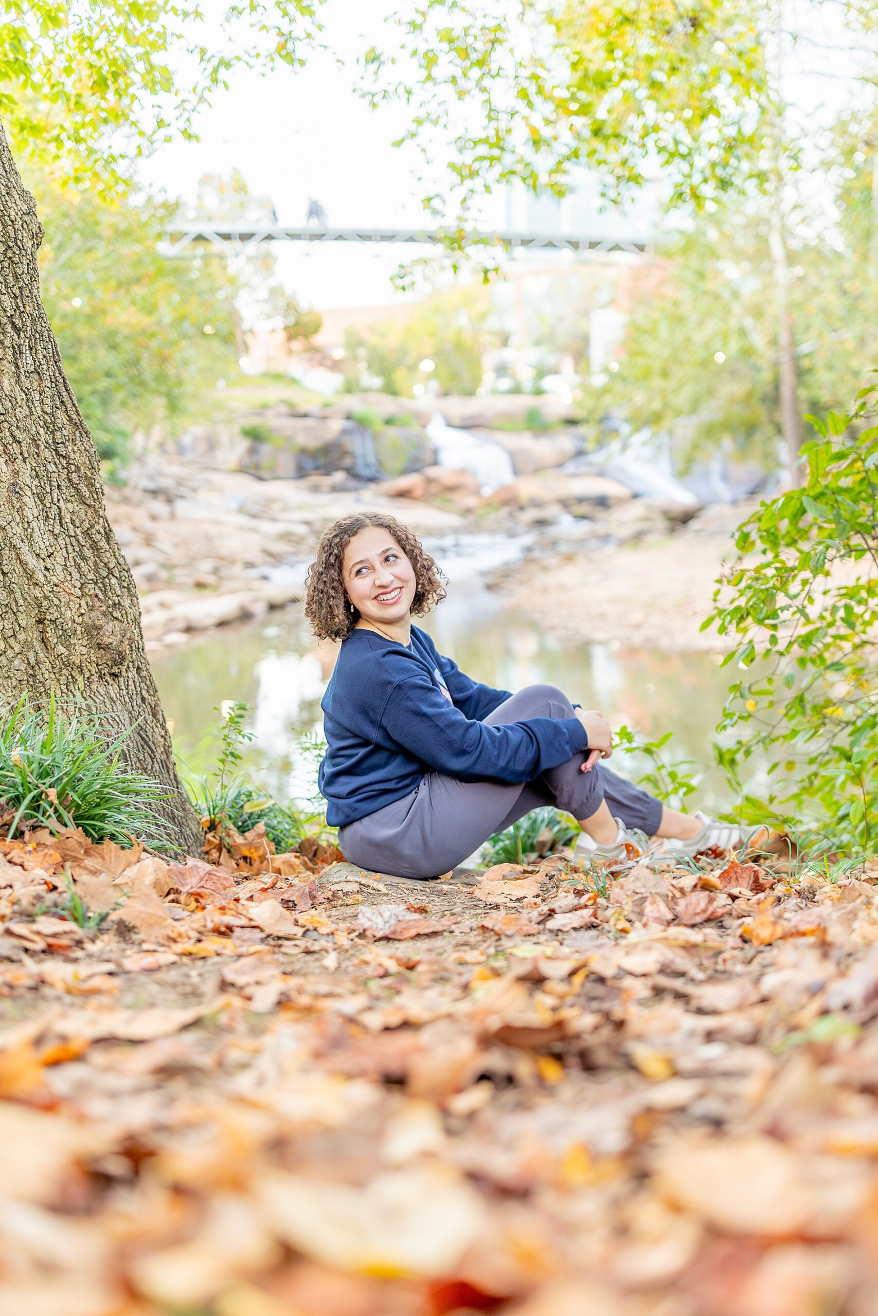 senior sits on ground during fall portrait s