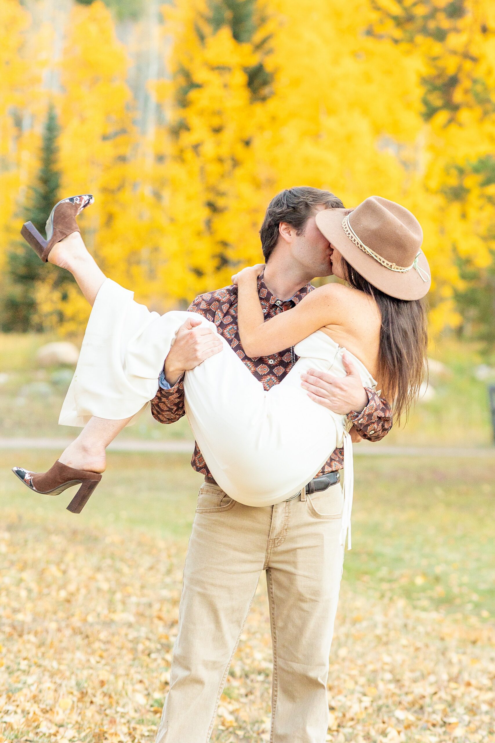 groom holds bride-to-be in arms as they kiss | Colorado Wedding at Beyul Retreat