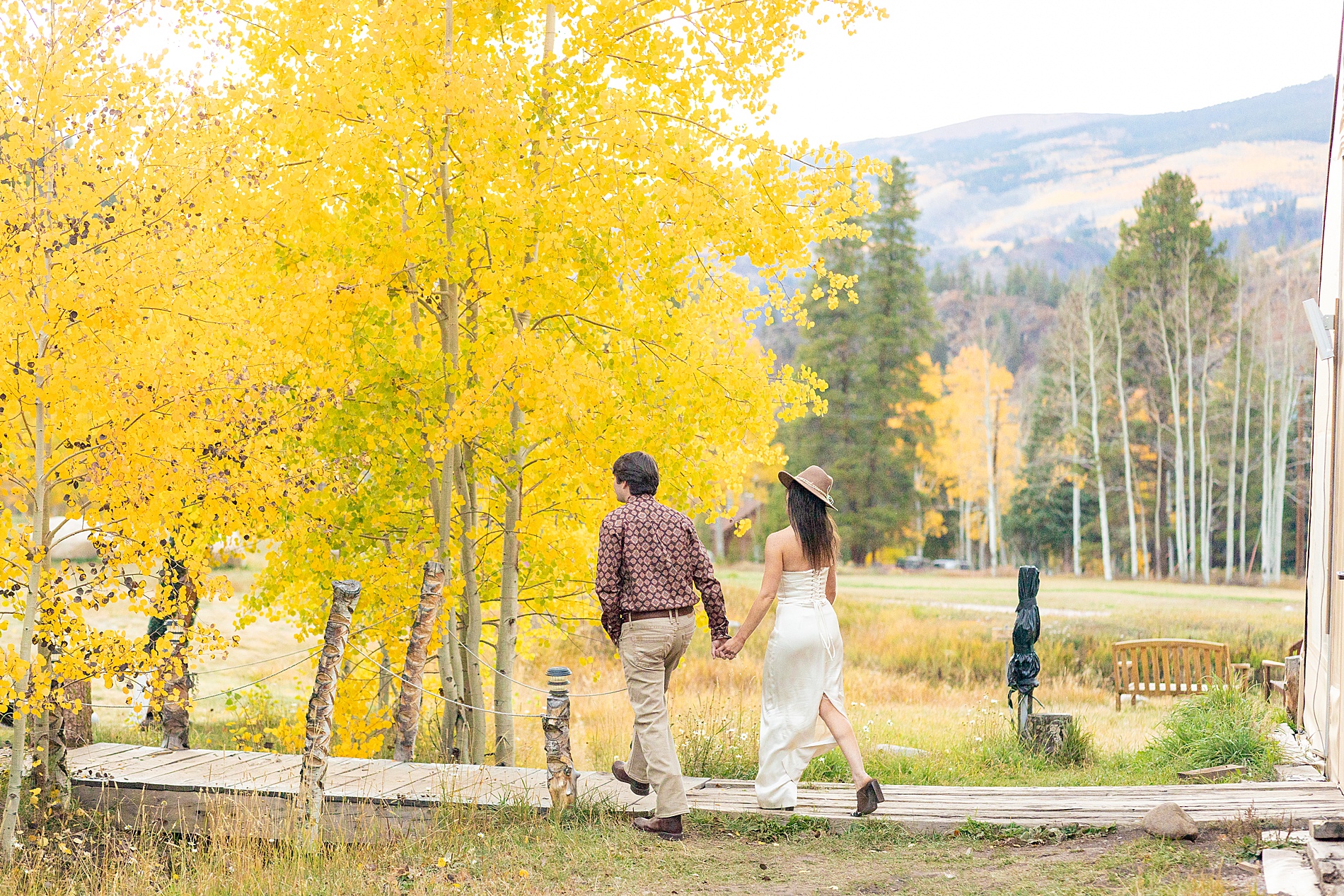 couple walk away under fall trees