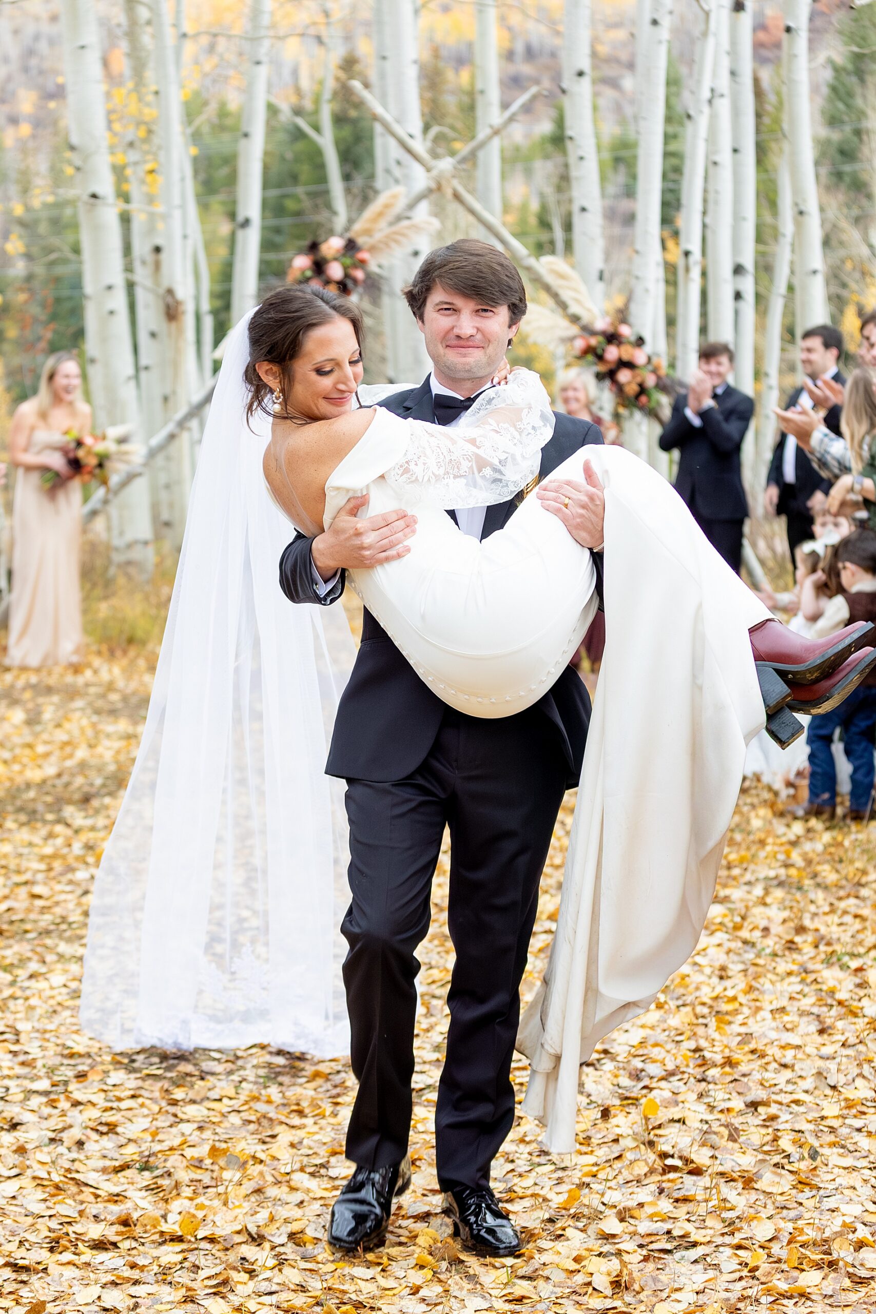 groom carries bride as they exit Colorado Wedding at Beyul Retreat