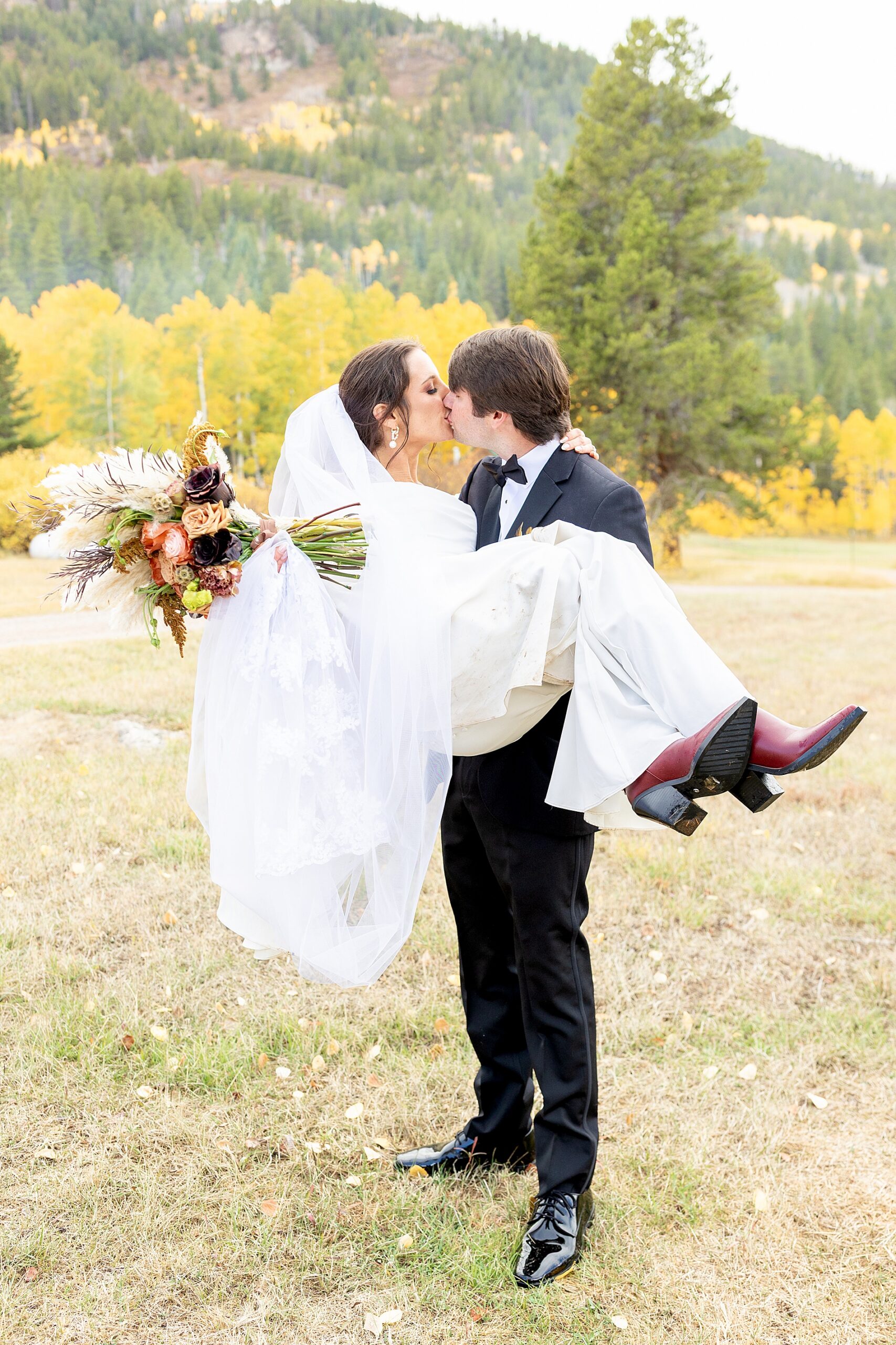 couple kissing as groom carries bride | Colorado Wedding at Beyul Retreat