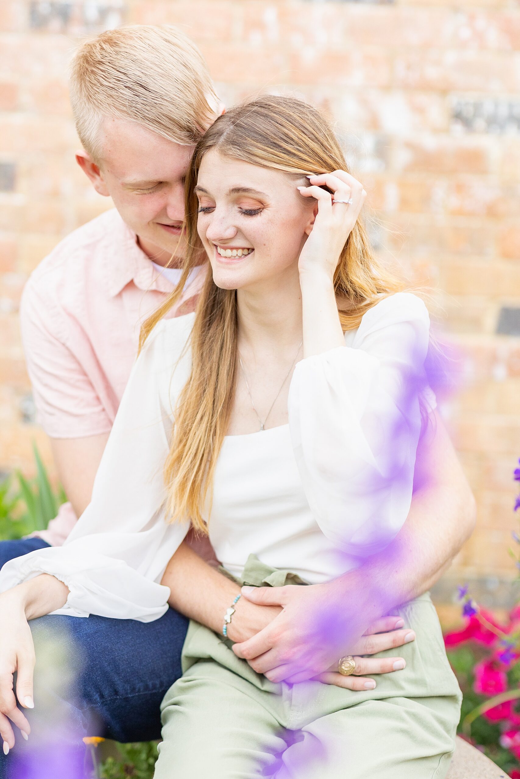 couple sit together surrounded by blooming flowers