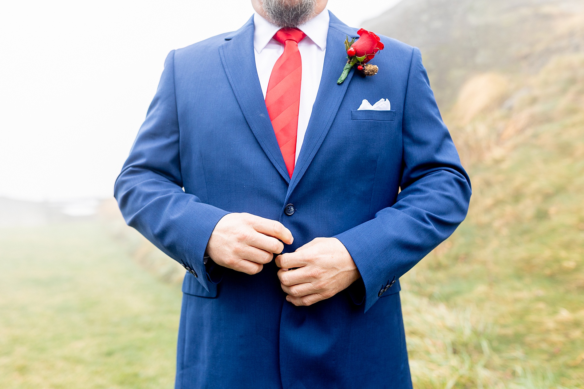 groom in blue suite with red tie