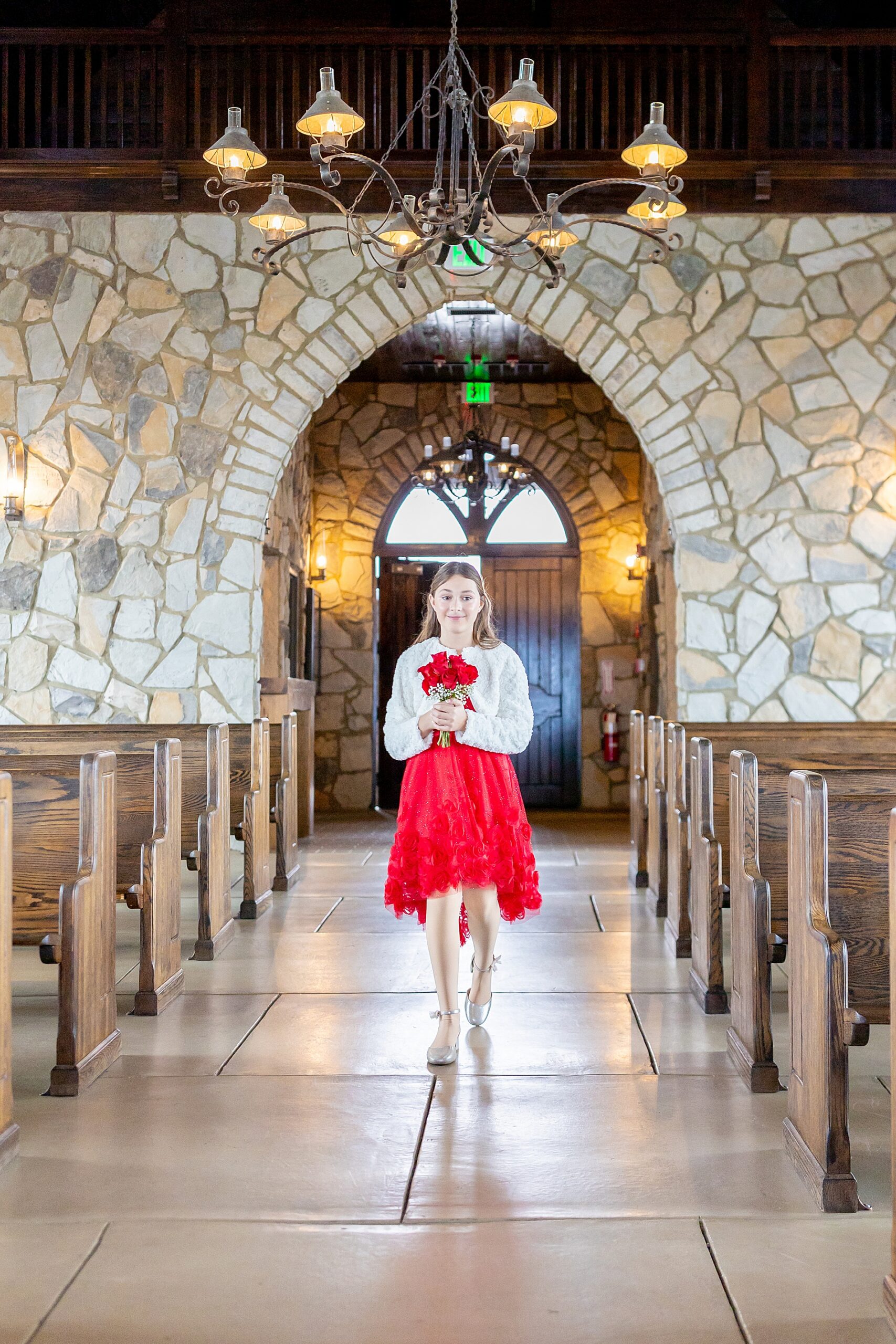 bride's daughter walking down the aisle in red dress