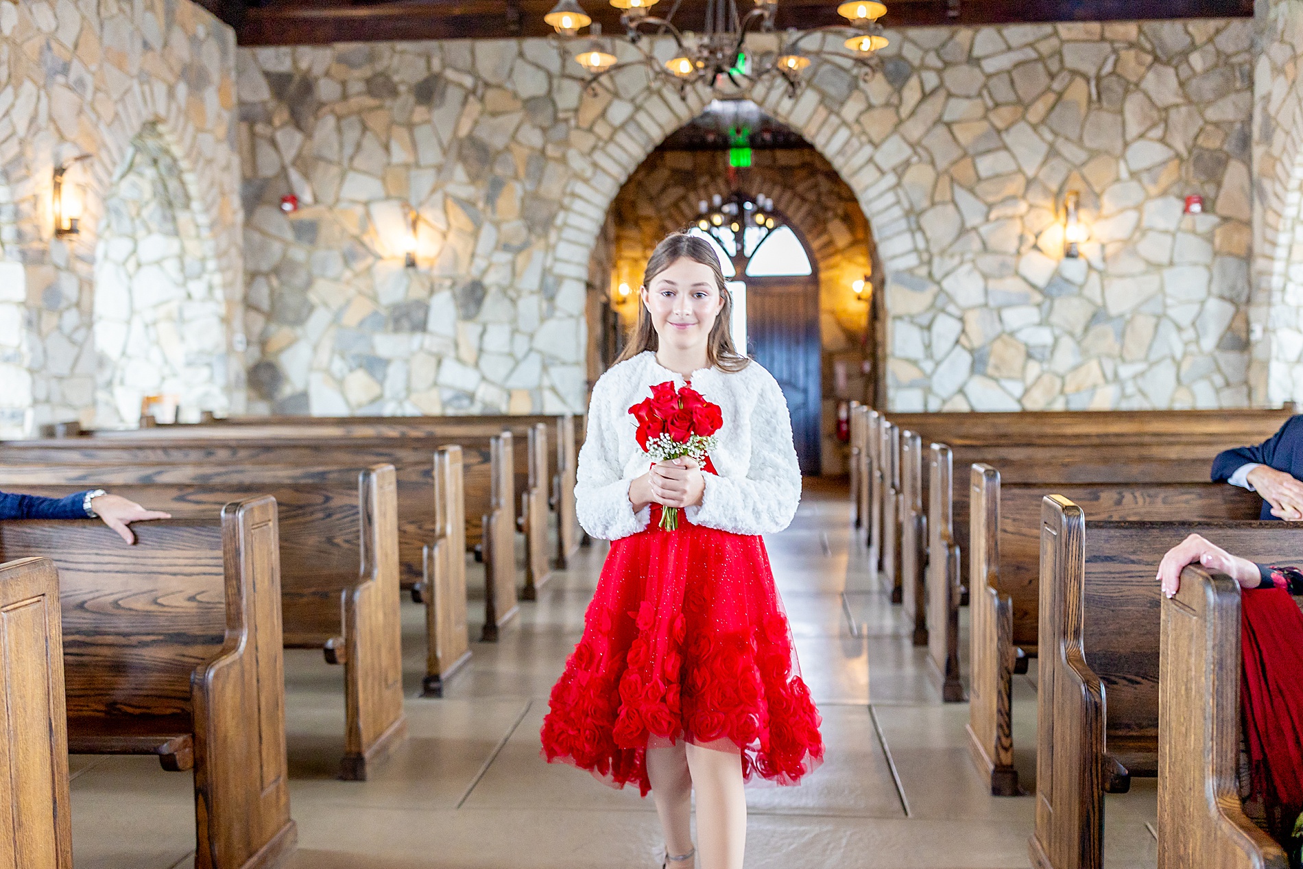 girl in red dress walking down the aisle at wedding 