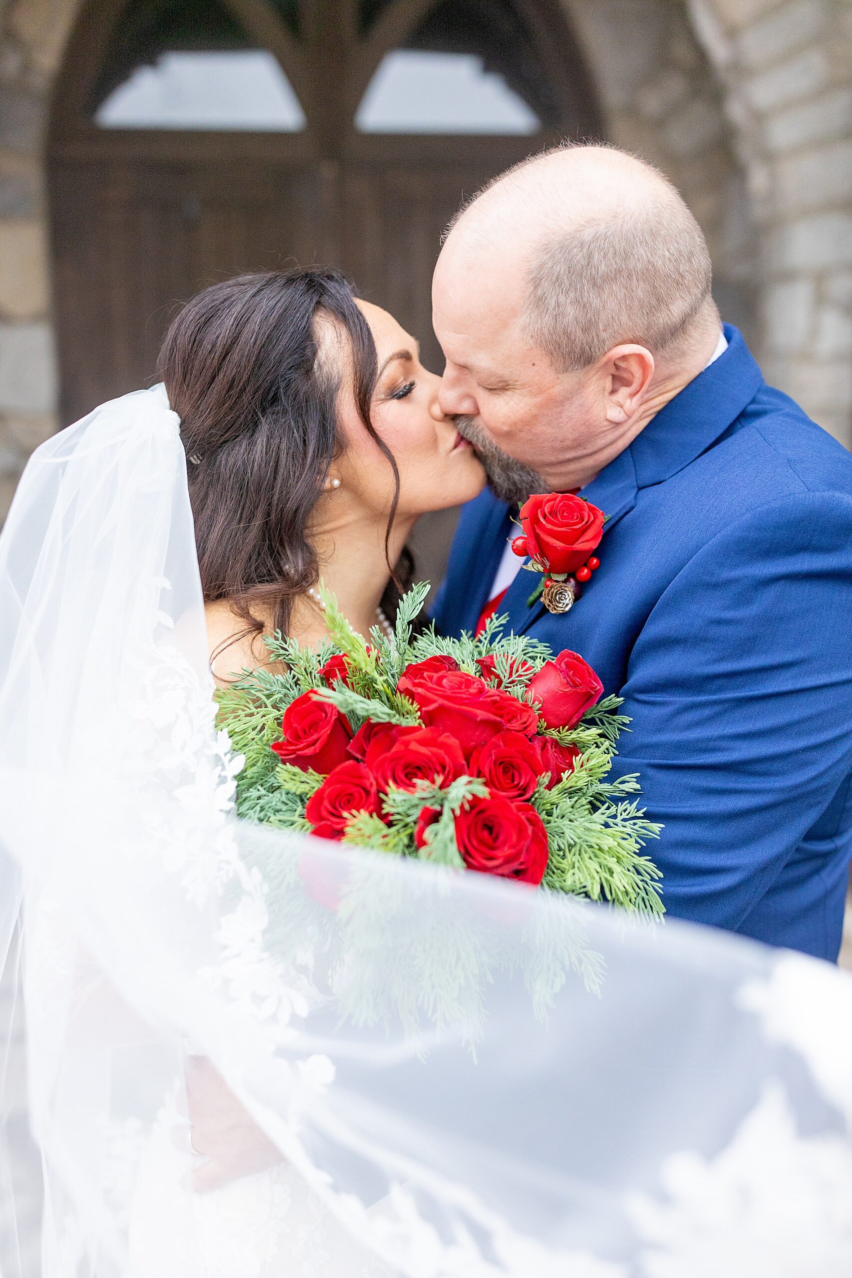 newlyweds kiss while bride's veil covers them 