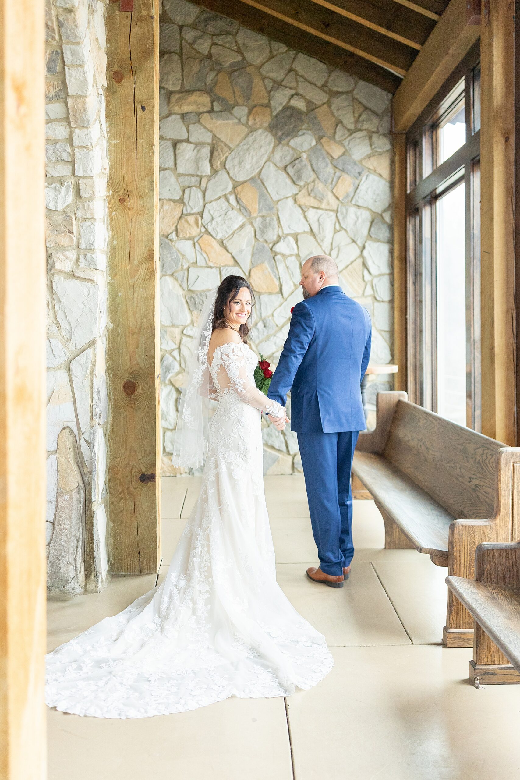 bride and groom hold hands by windows of chapel