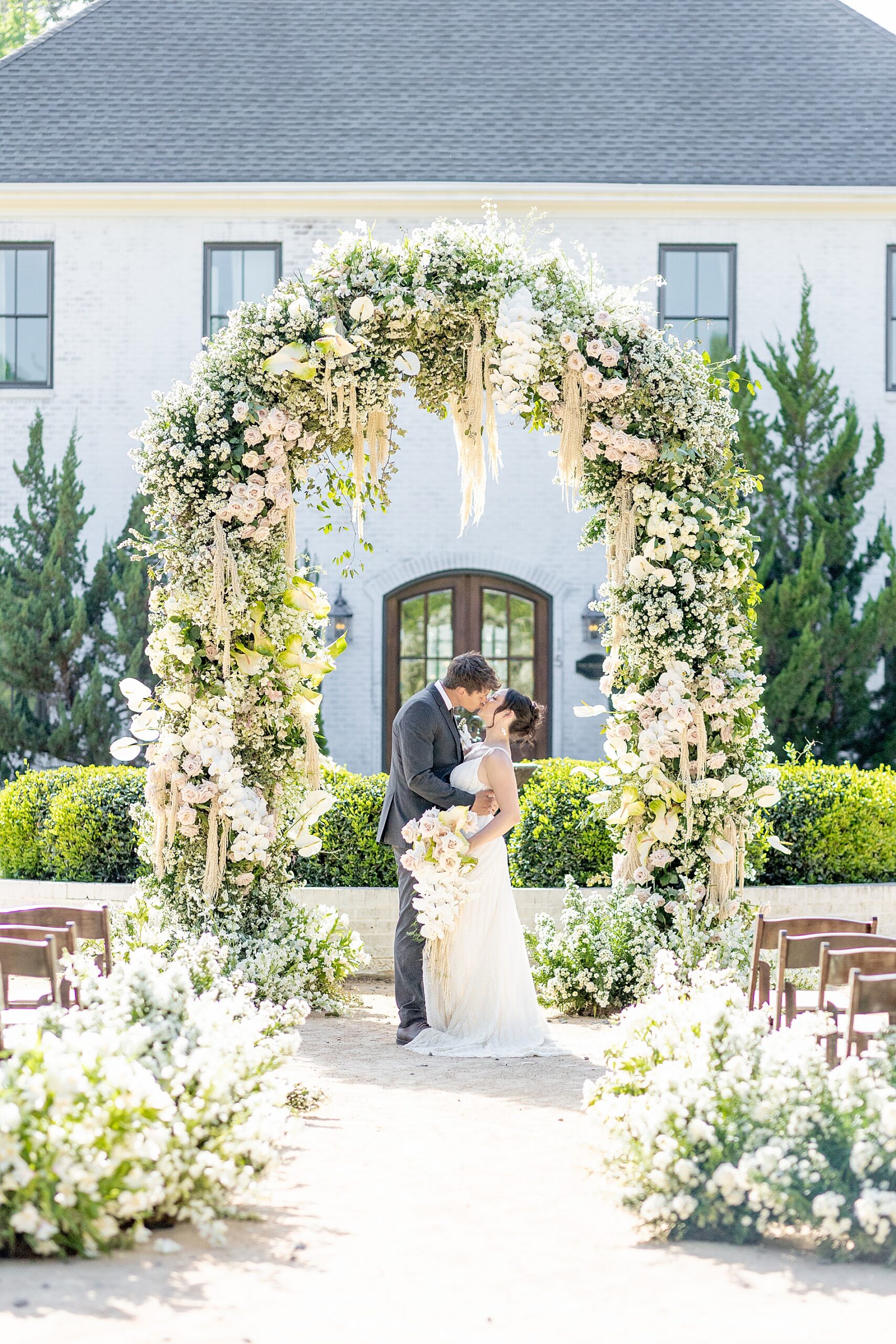 newlyweds kiss under floral arch