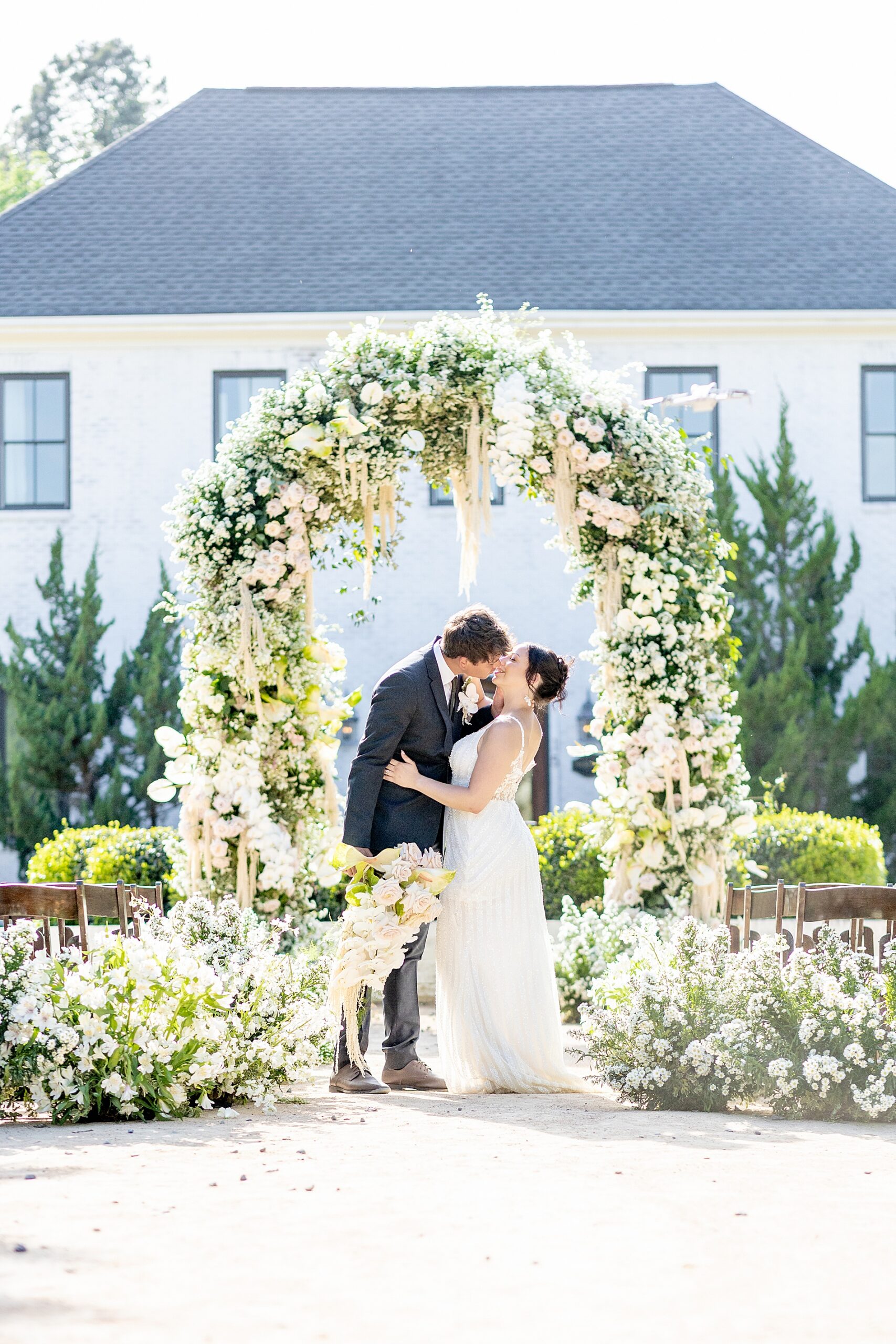 bride and groom portraits under floral arch during Raleigh NC wedding