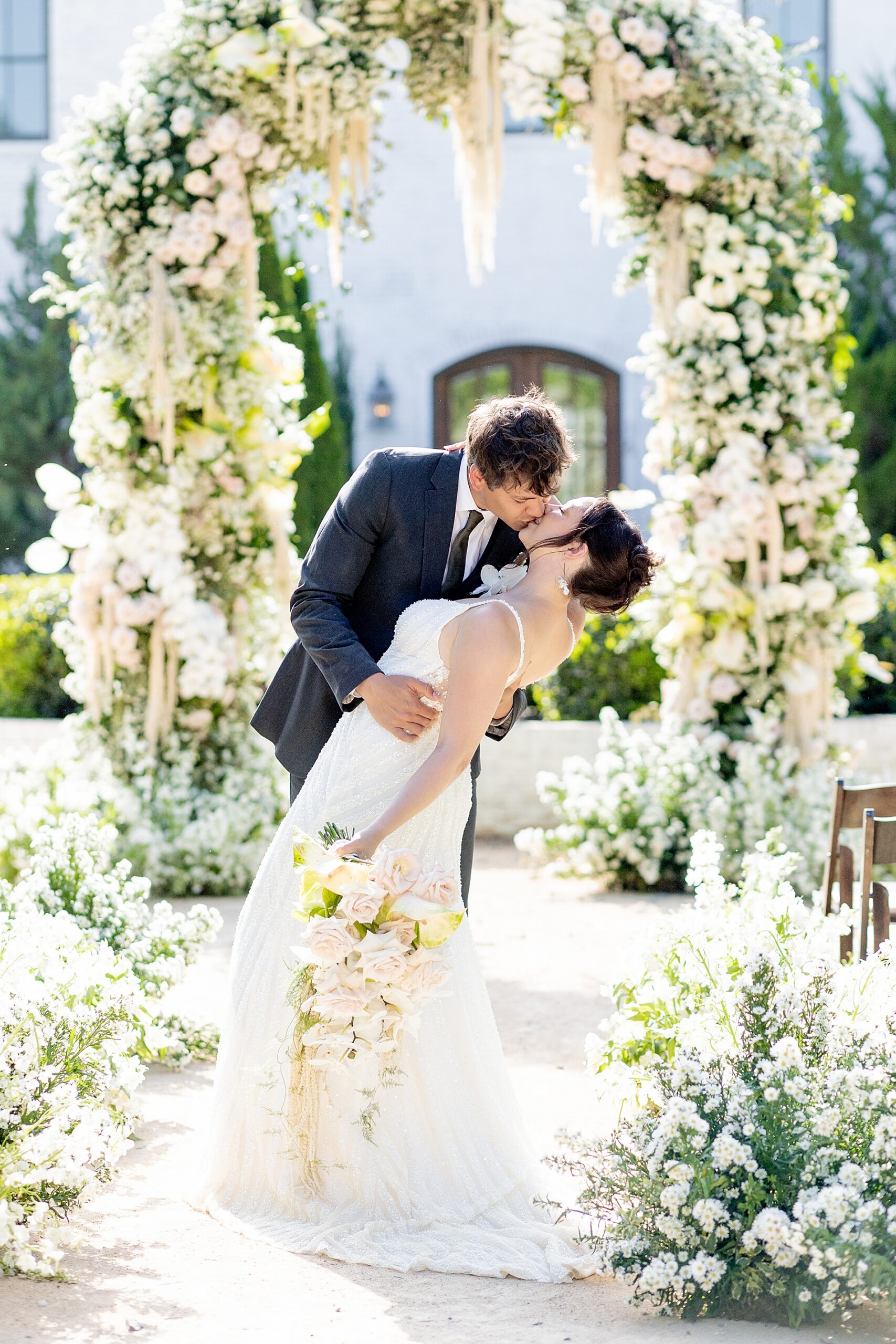romantic wedding portraits of bride and groom kissing surrounded by florals