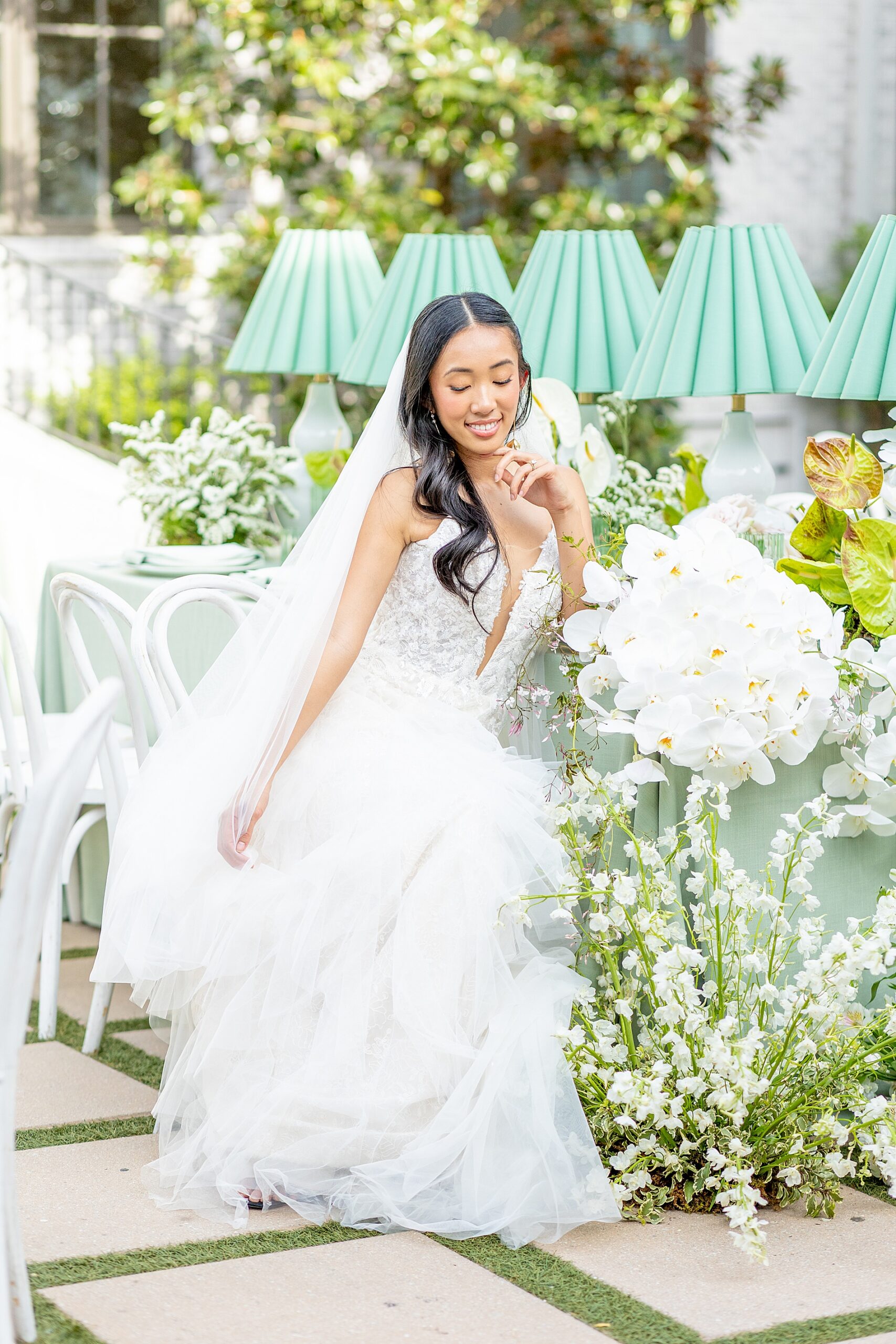 bride sits at reception table surrounded by florals 