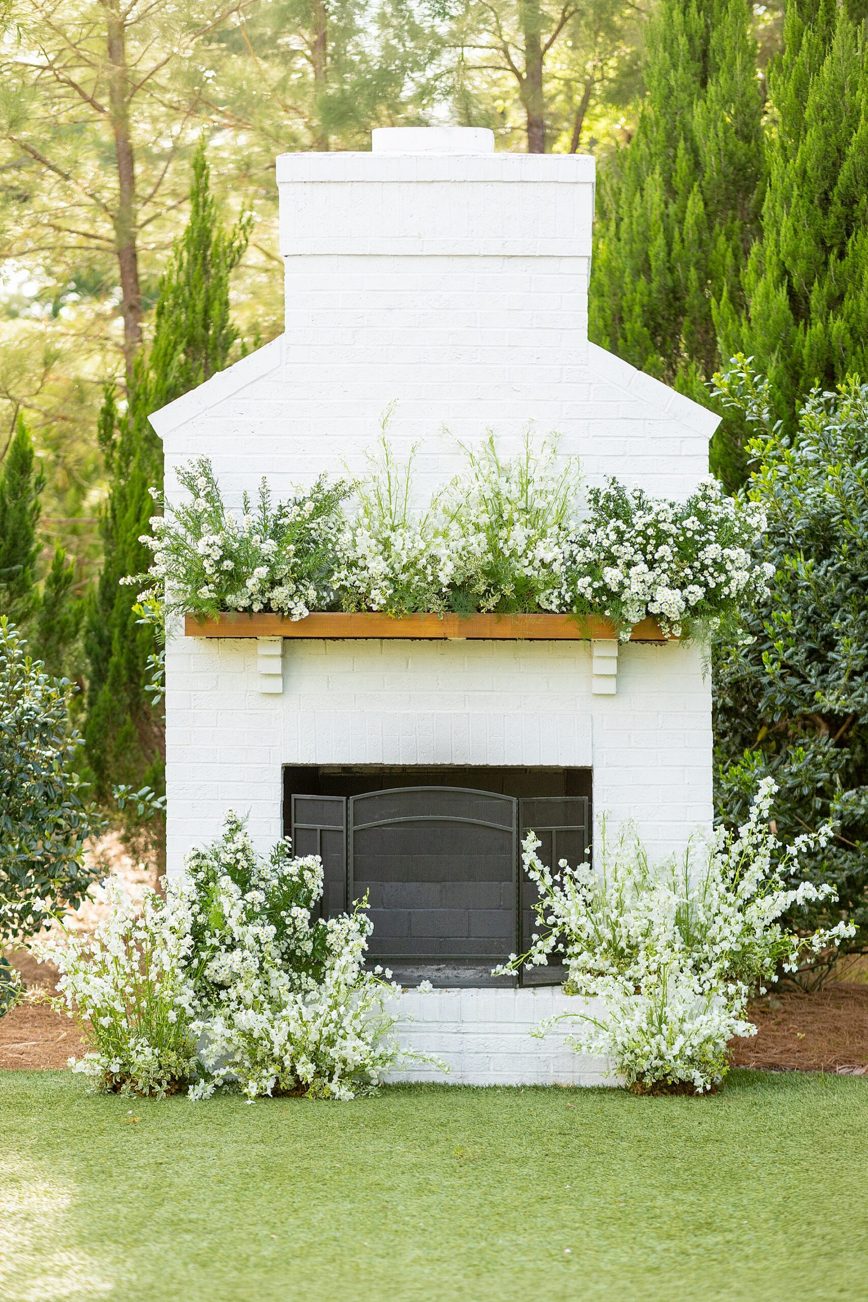 outdoor fireplace decorated with white flowers and greenery 